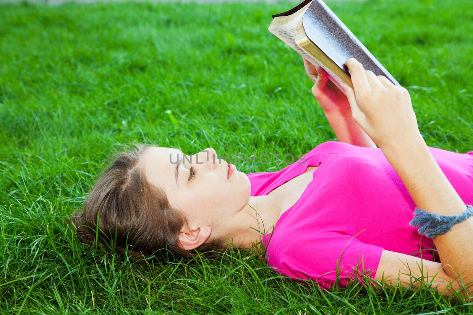 Teen girl reading the Bible outdoors by AndreyKr