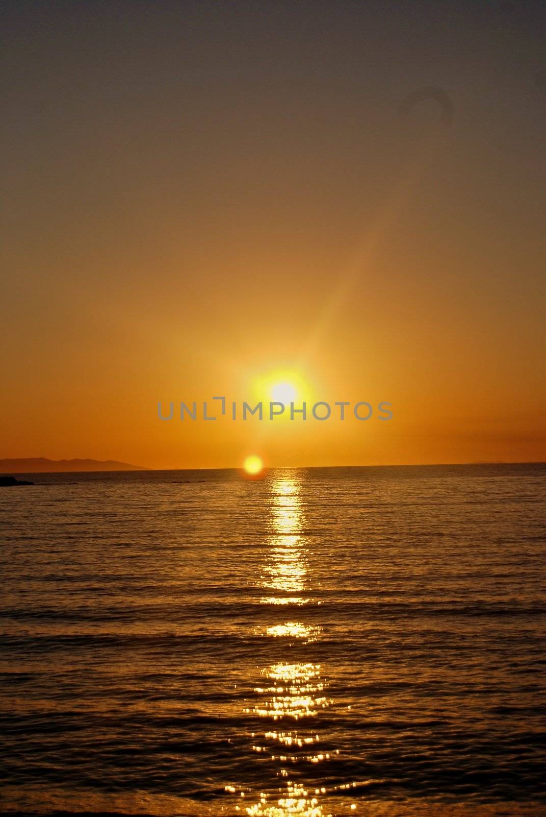 The sun sets over beach with beautiful reflection by Bildehagen