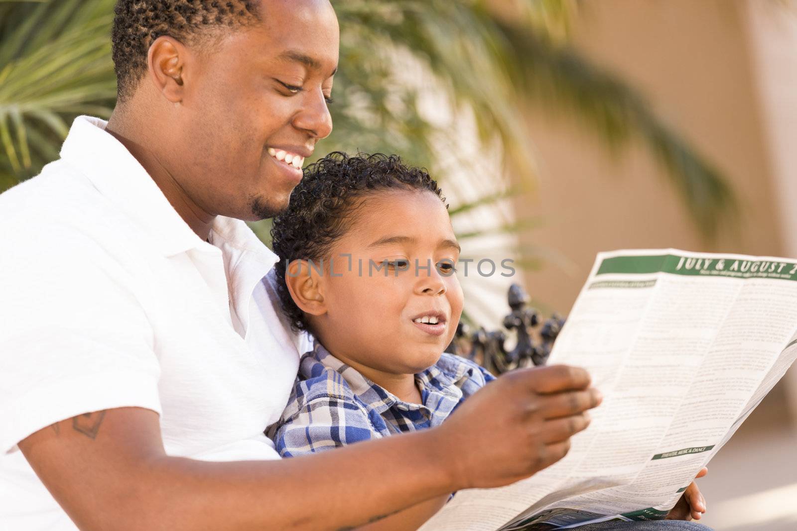 Happy African American Father and Mixed Race Son Having Fun Reading Park Brochure Outside.