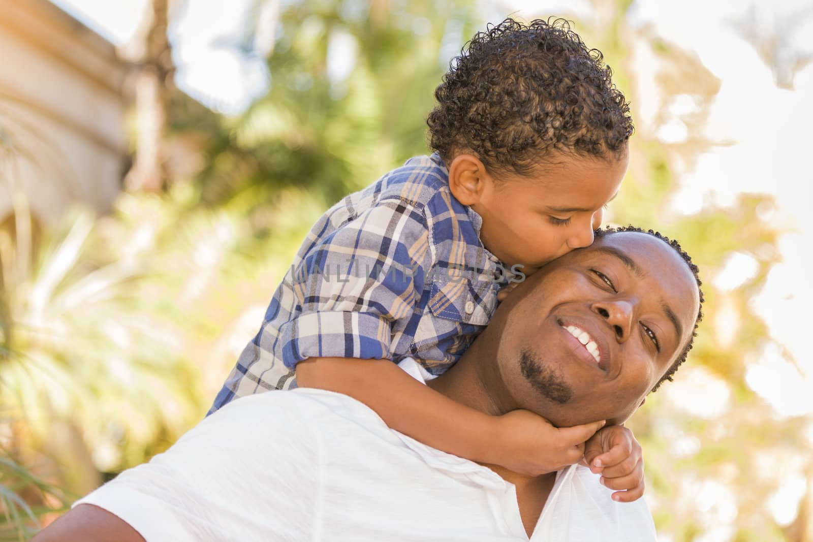 Mixed Race Father and Son Playing Piggyback in Park by Feverpitched