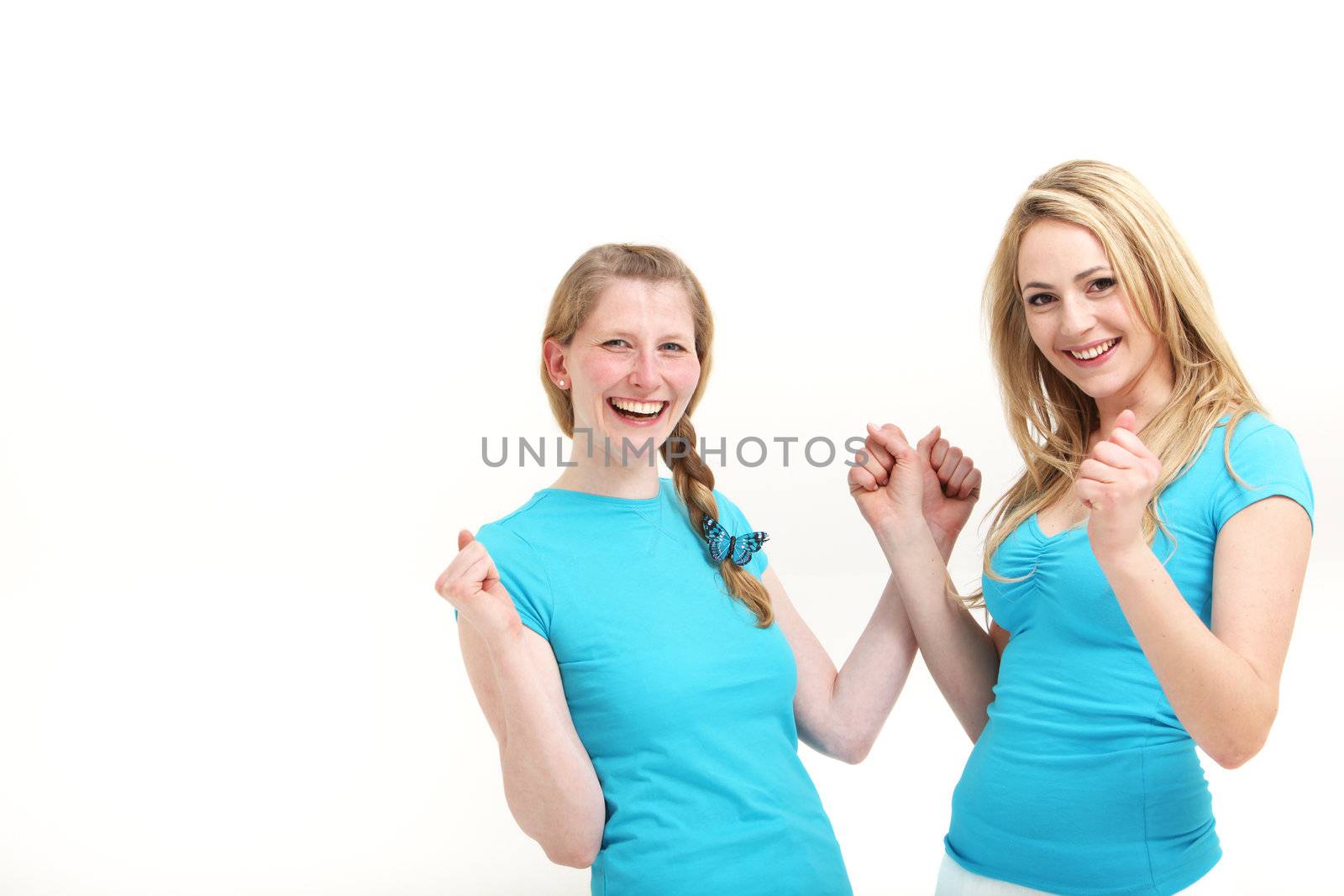 Two young women laughing with jubilation as they raise their clenched hands in the air to signal their success