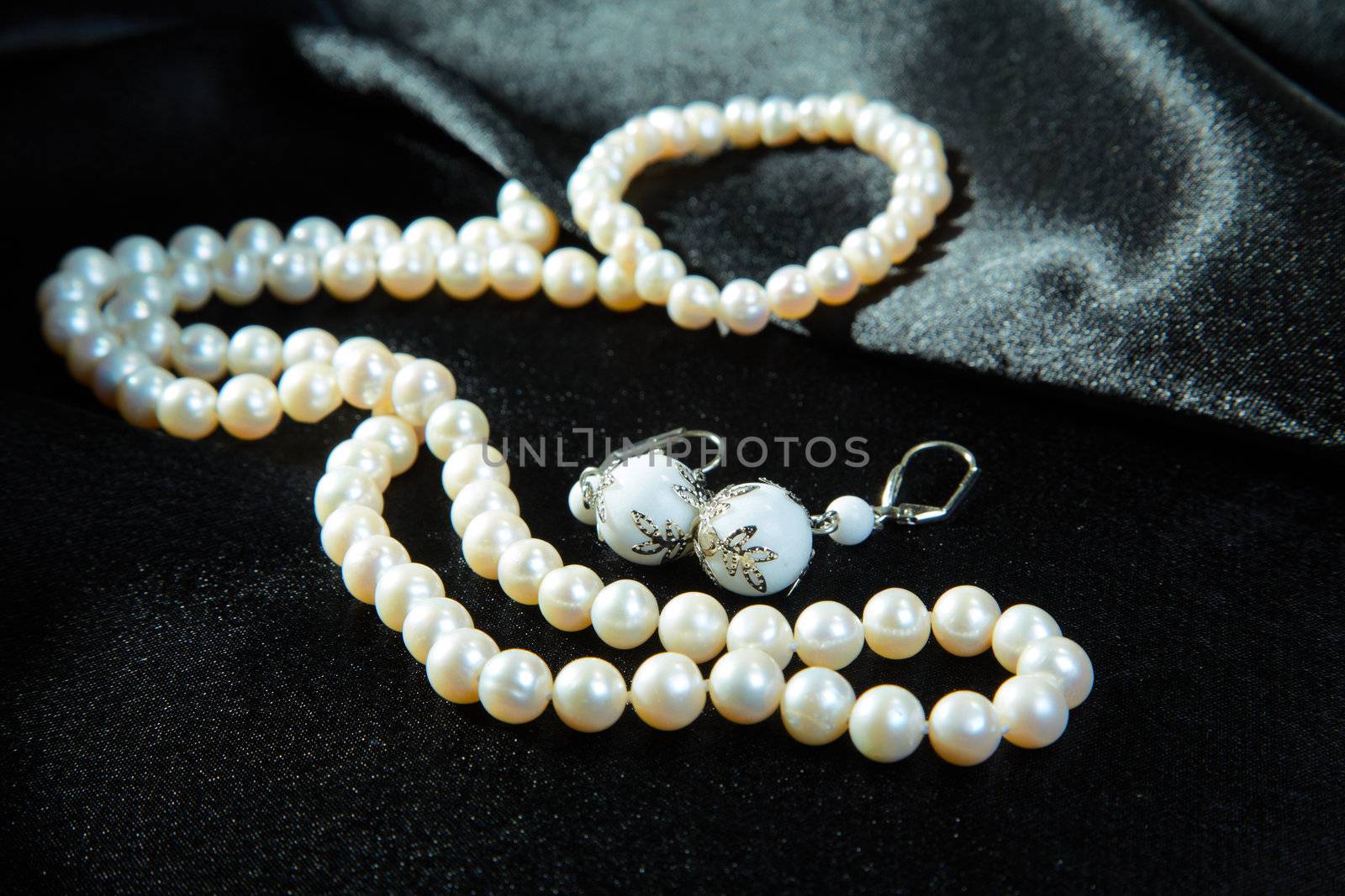  White necklace and earrings on a black fabric