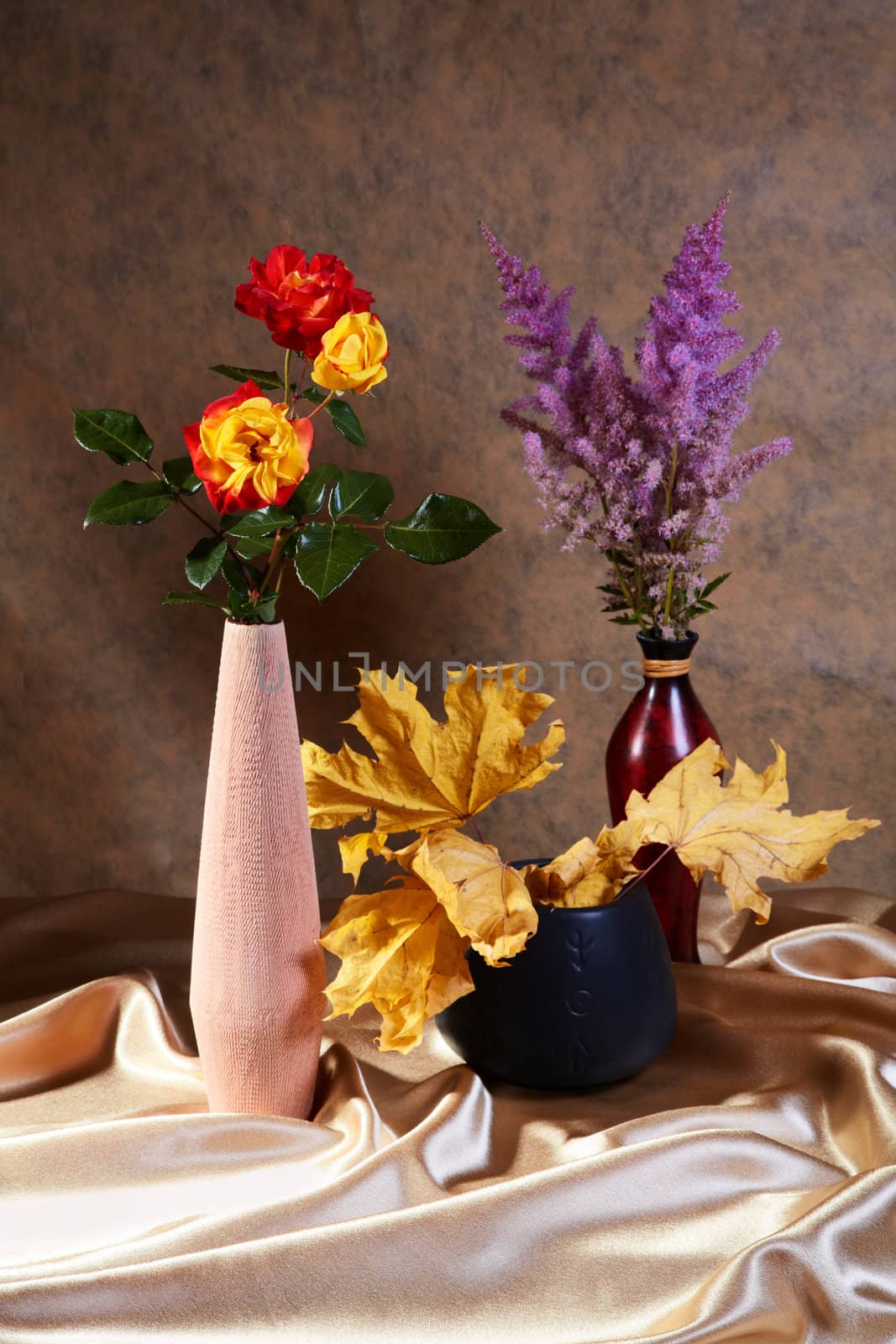 Still-life with roses and dry maple leaves in vases