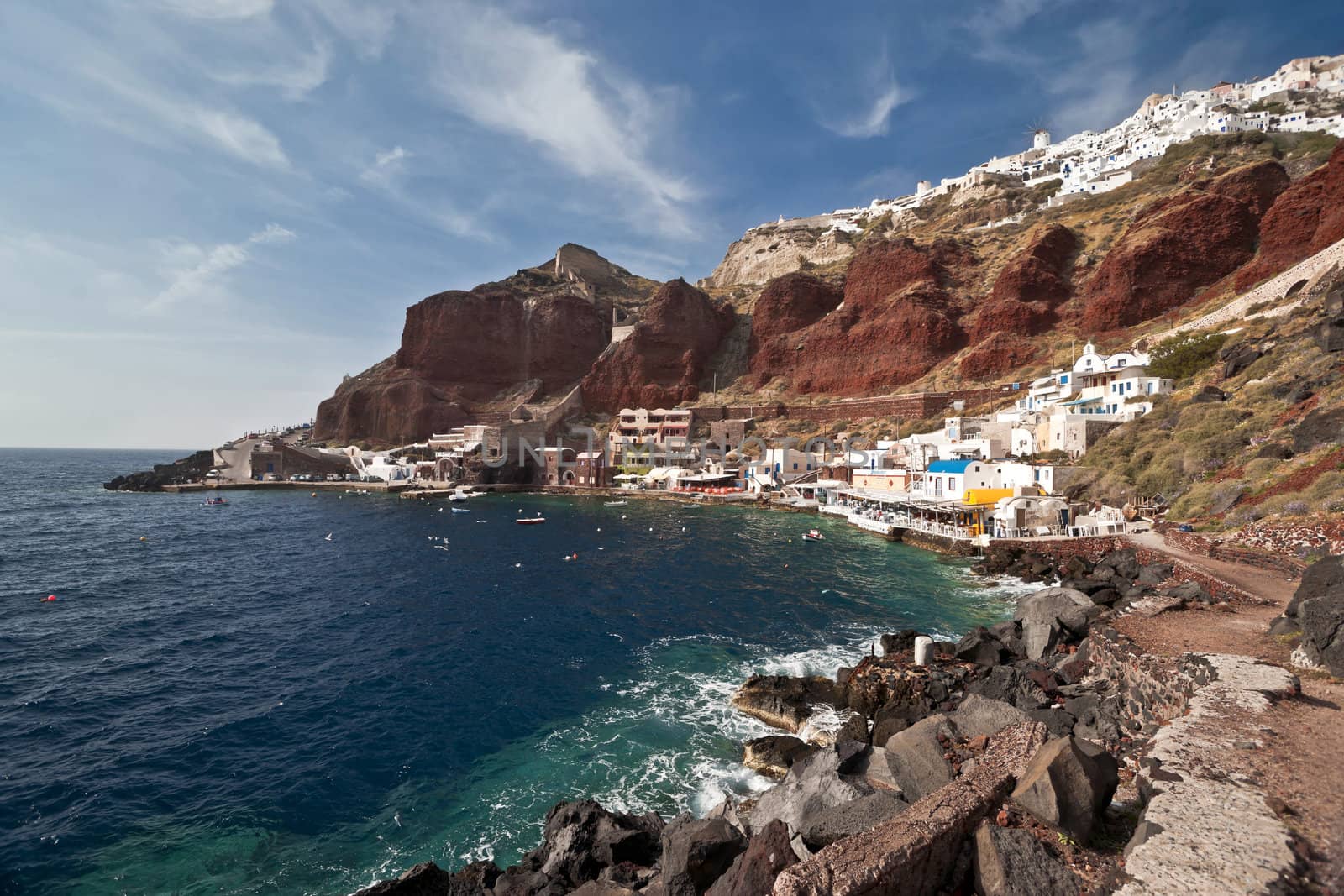 Ia houses view with volcanic rock of red and black colors and the port below