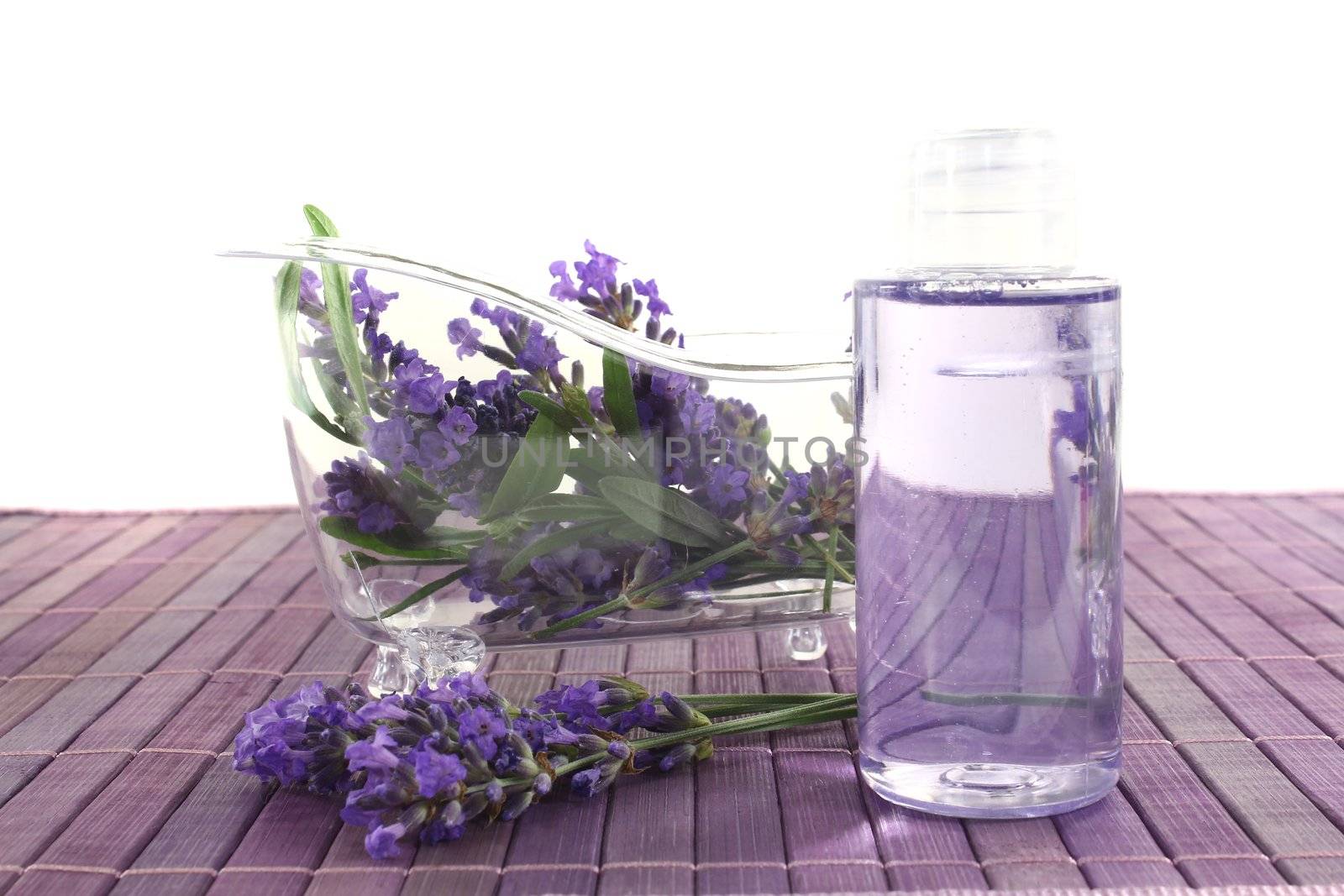 Lavender oil before a bath with flowers and leaves on bright background