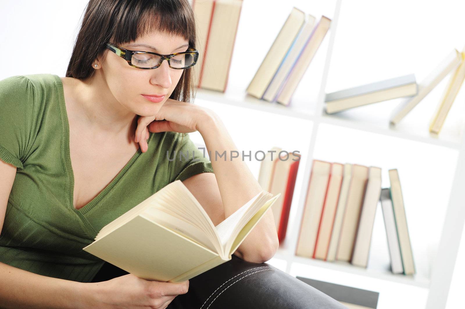 bright picture of young woman woman with book , bookshelf on bac by stokkete