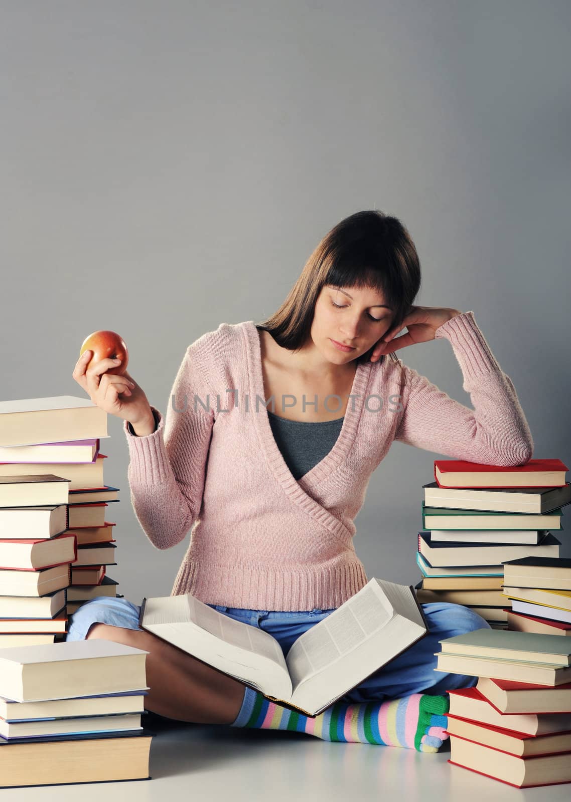 Cute girl studying with a big stack of books by stokkete