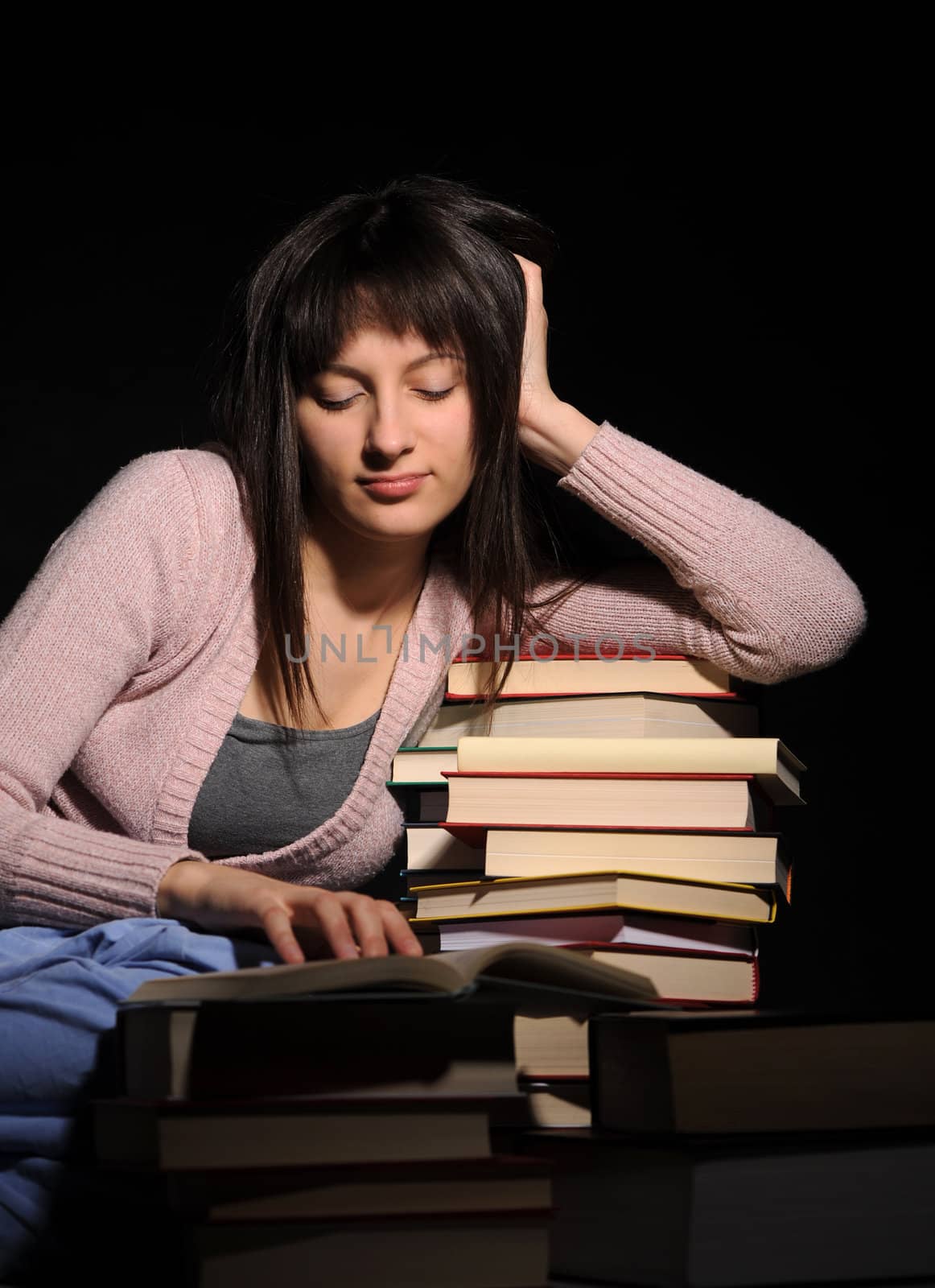 Cute girl studying with a big stack of books by stokkete