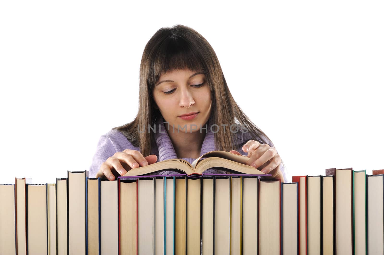 young woman reading a book behind a big pile of books  by stokkete