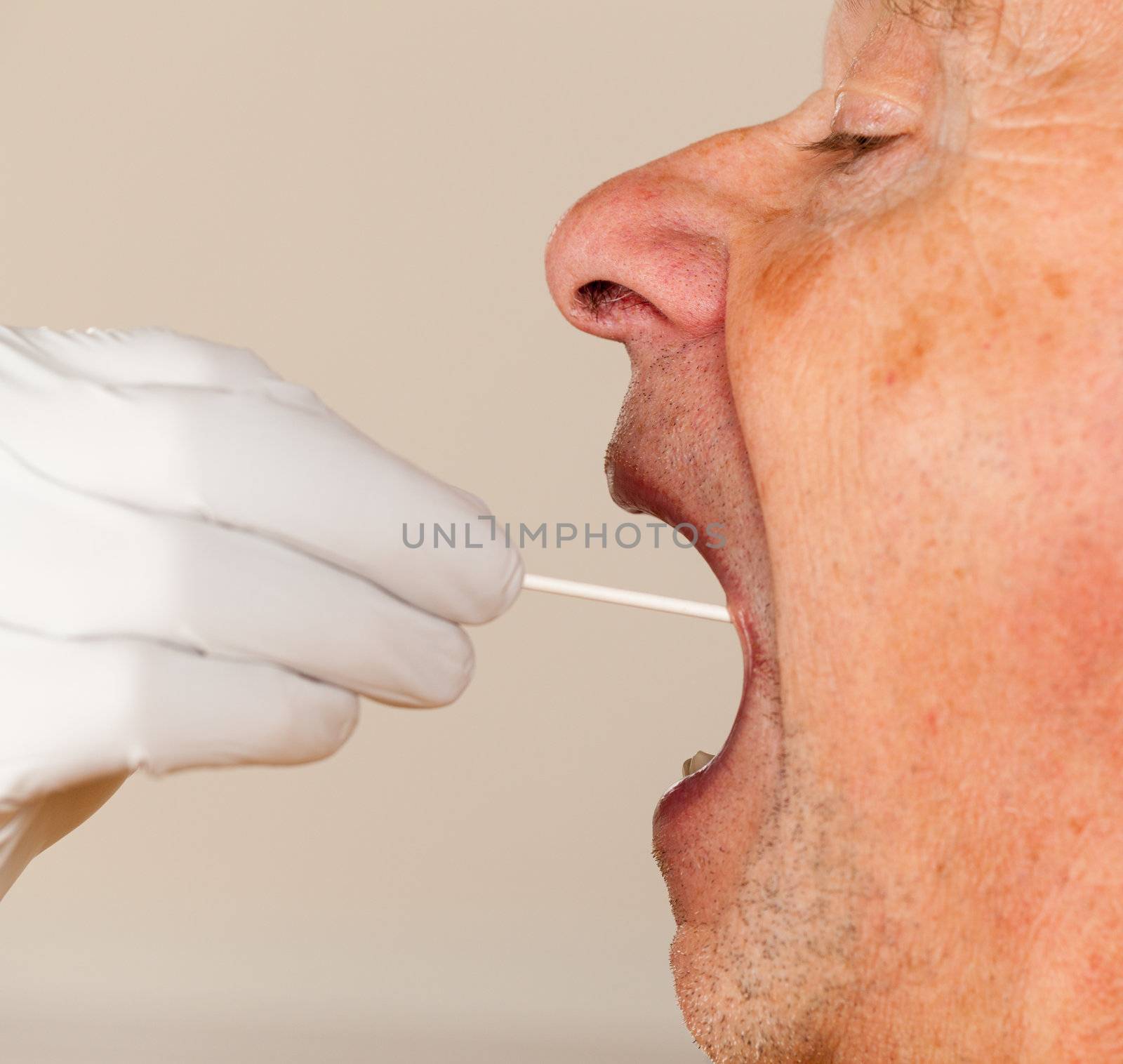 Gloved hand taking a bodily fluid sample for DNA test from senior male person