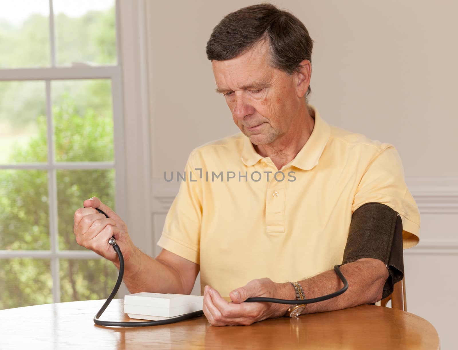 Senior man taking blood pressure at home by steheap