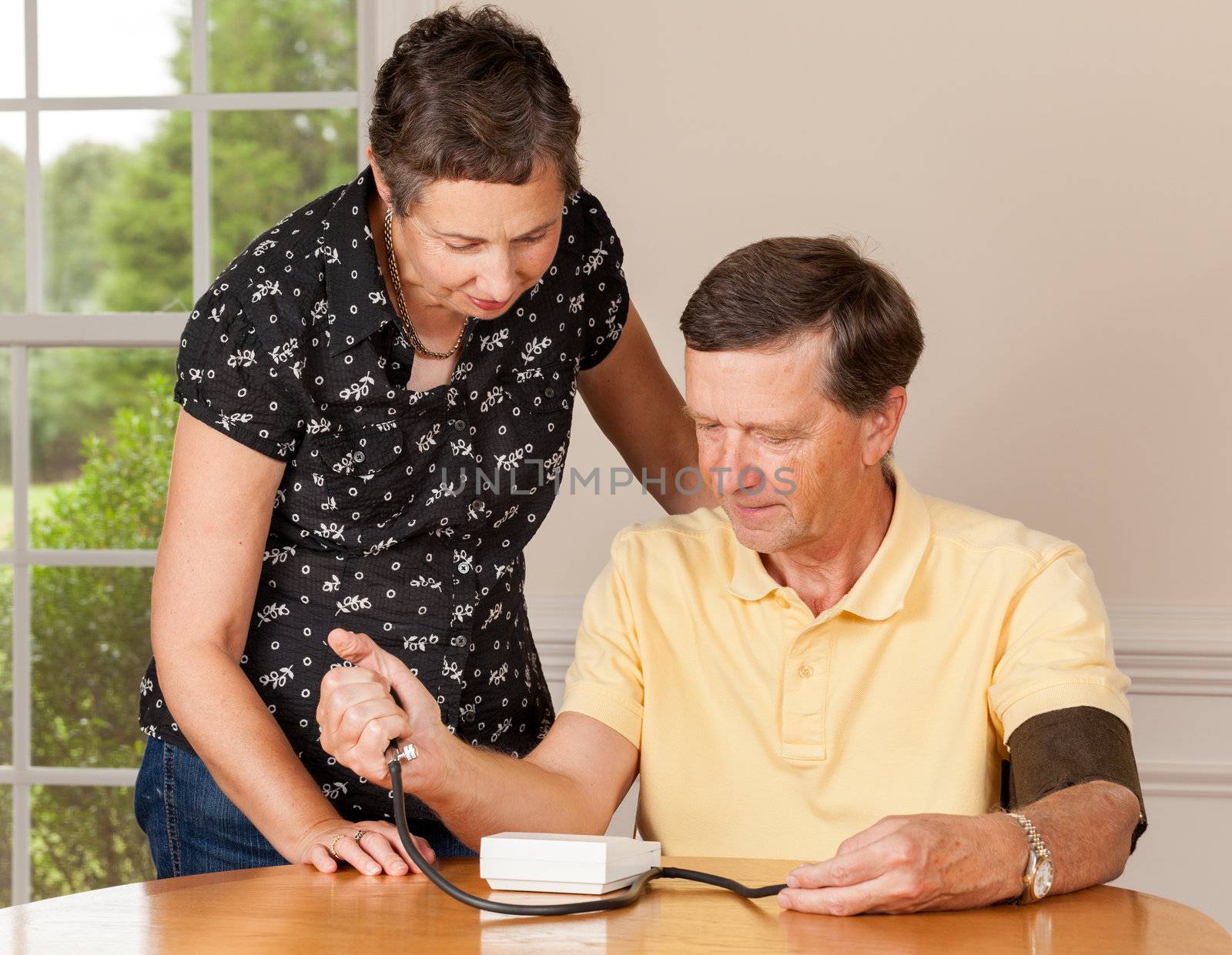 Senior man taking blood pressure with wife by steheap