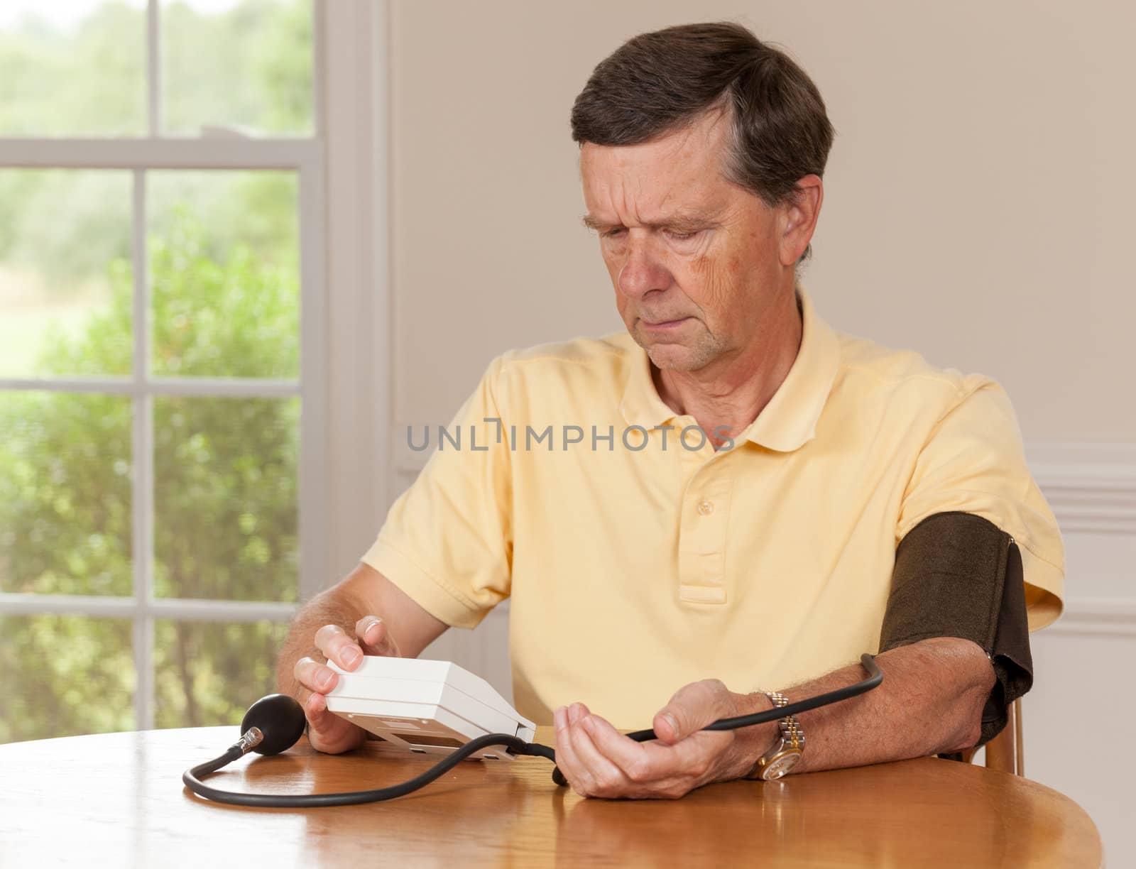 Senior man taking blood pressure at home by steheap