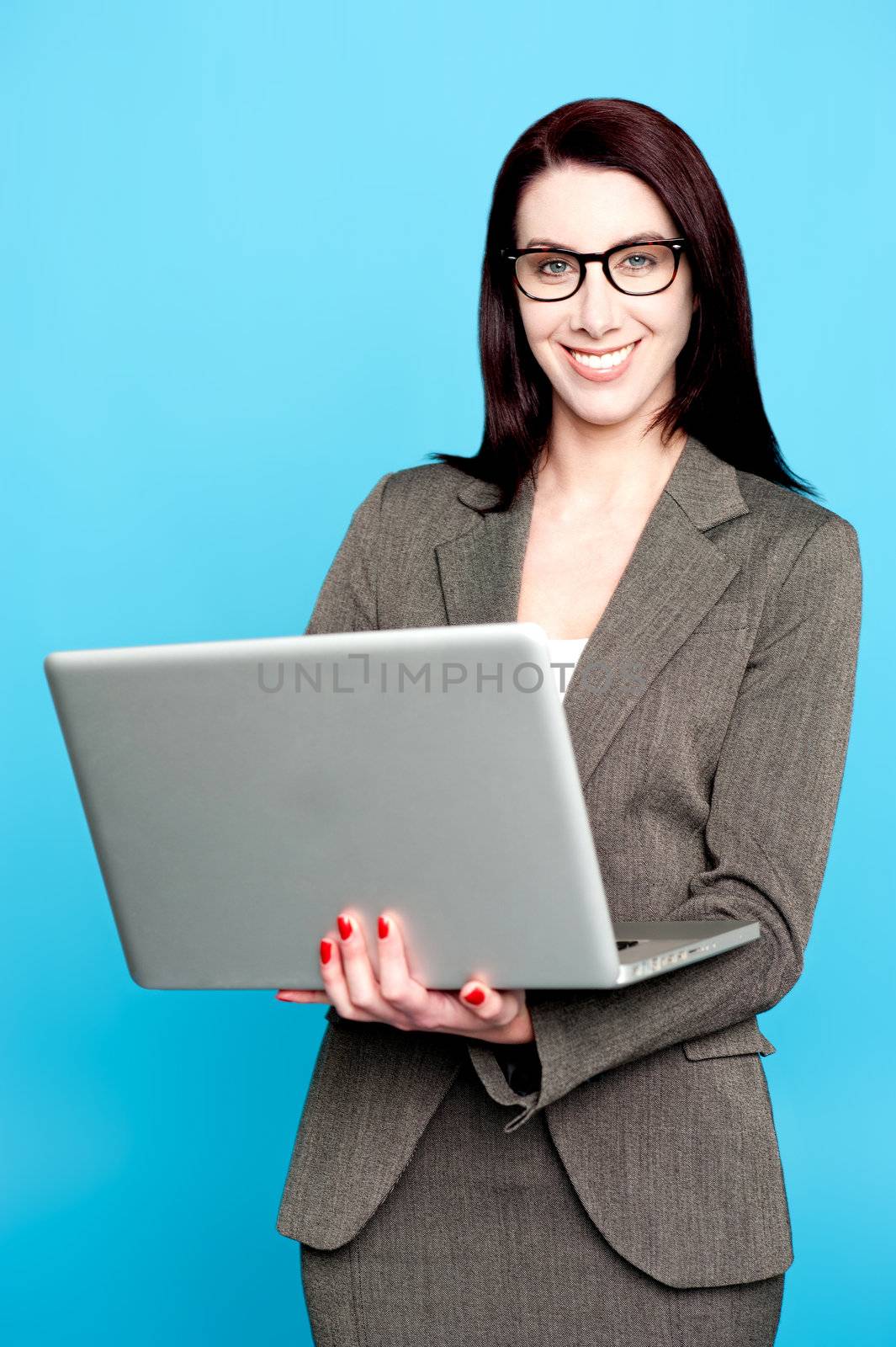 Young corporate woman working on laptop isolated against blue