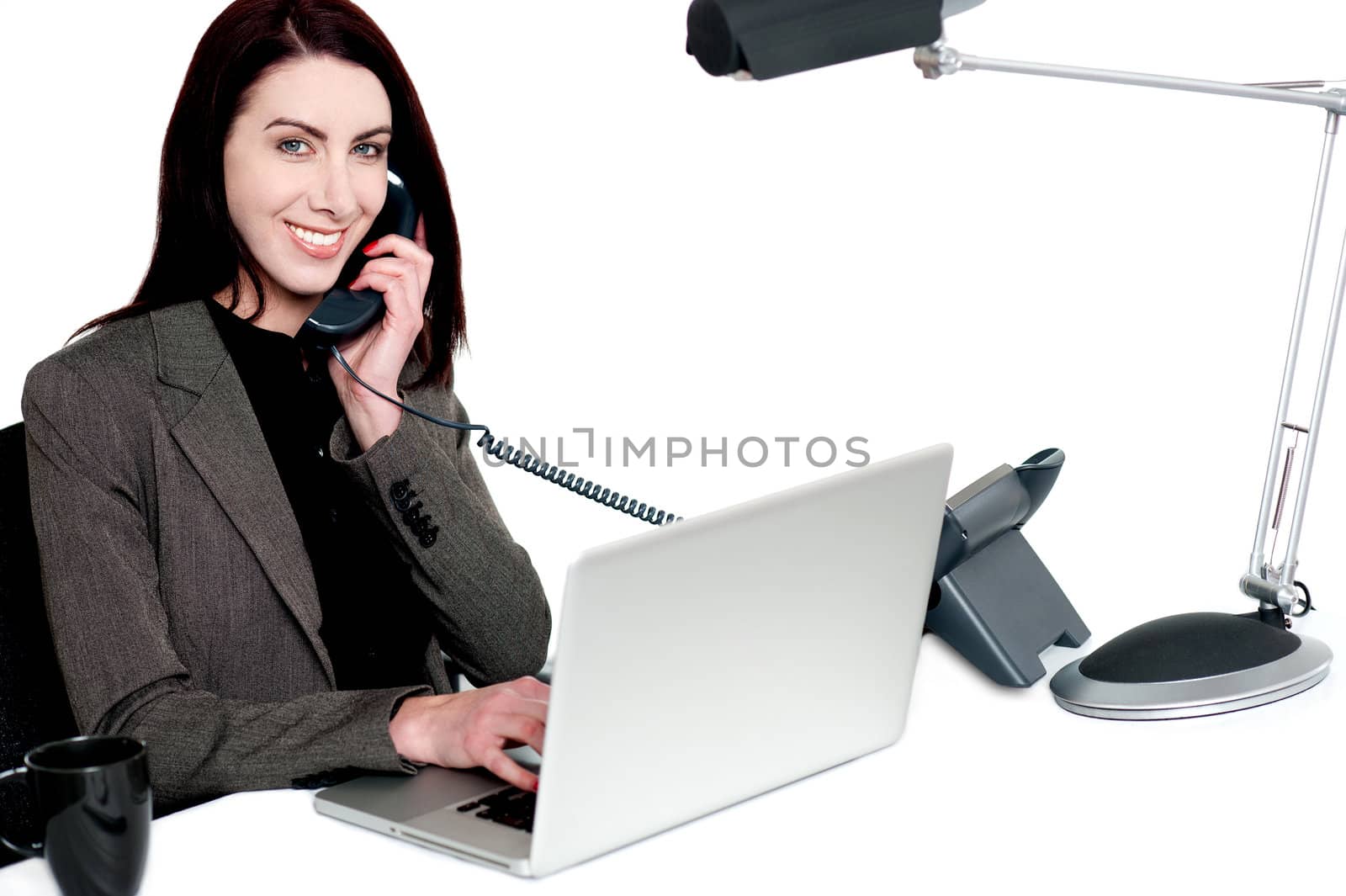 Female operator talking on phone and smiling. Actively working in office