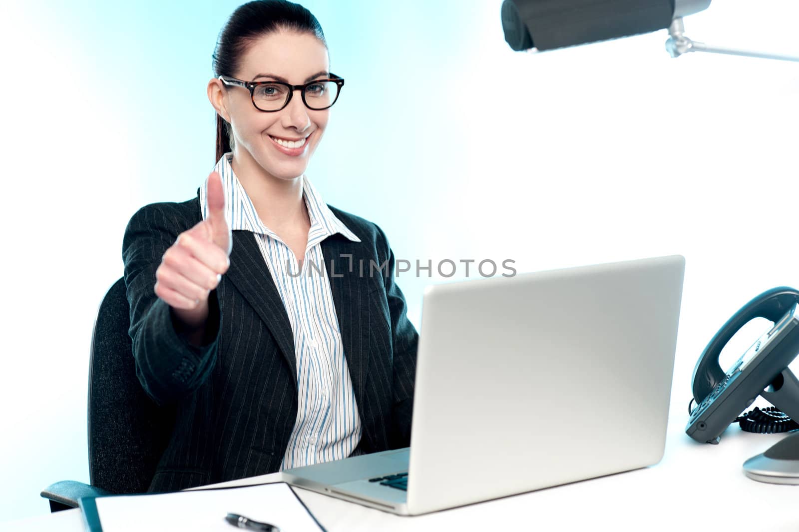 Confident businesswoman gesturing working on laptop and gesturing thumbs up