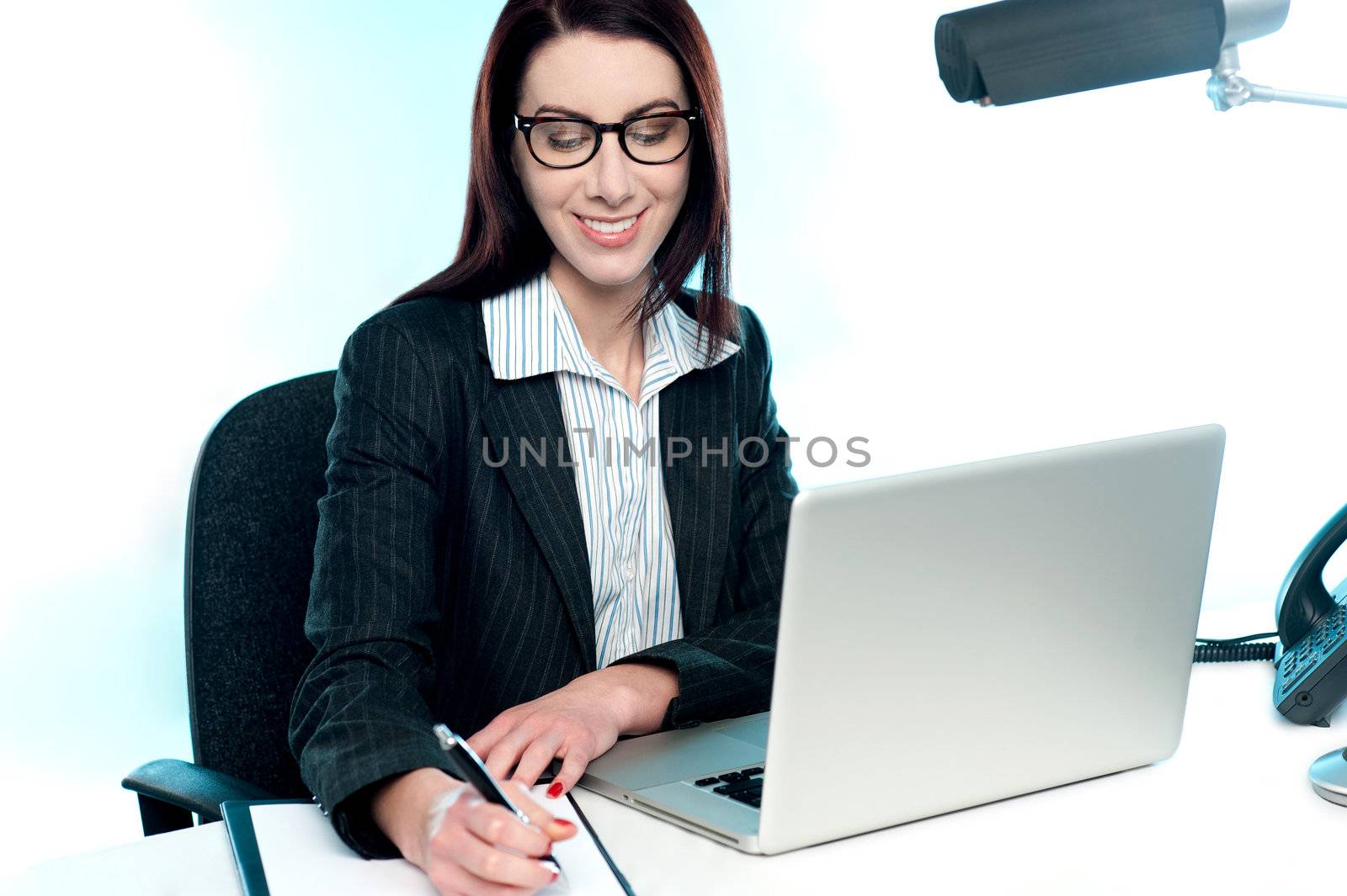 Smiling businesswoman writing an important document seated in office