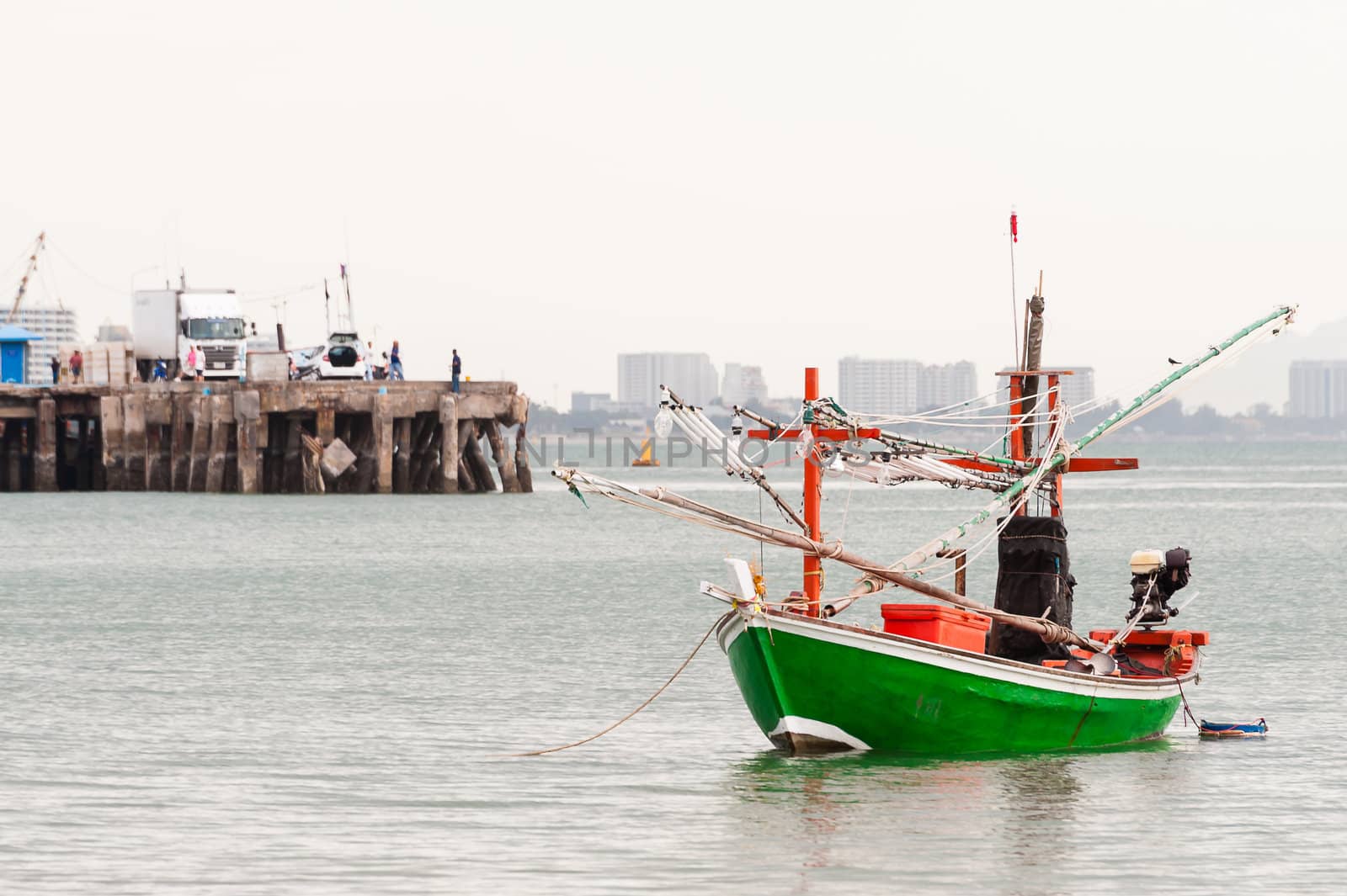 Green fishing boat thai on the sea in daylight time with jetty