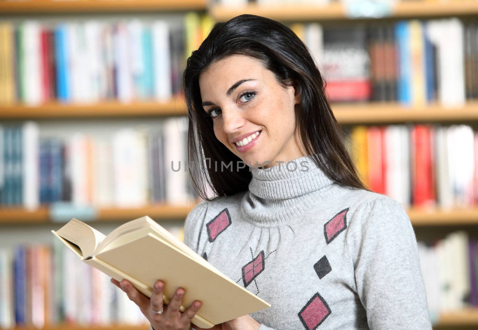 smiling female student with book in hands in a bookstore - model by stokkete
