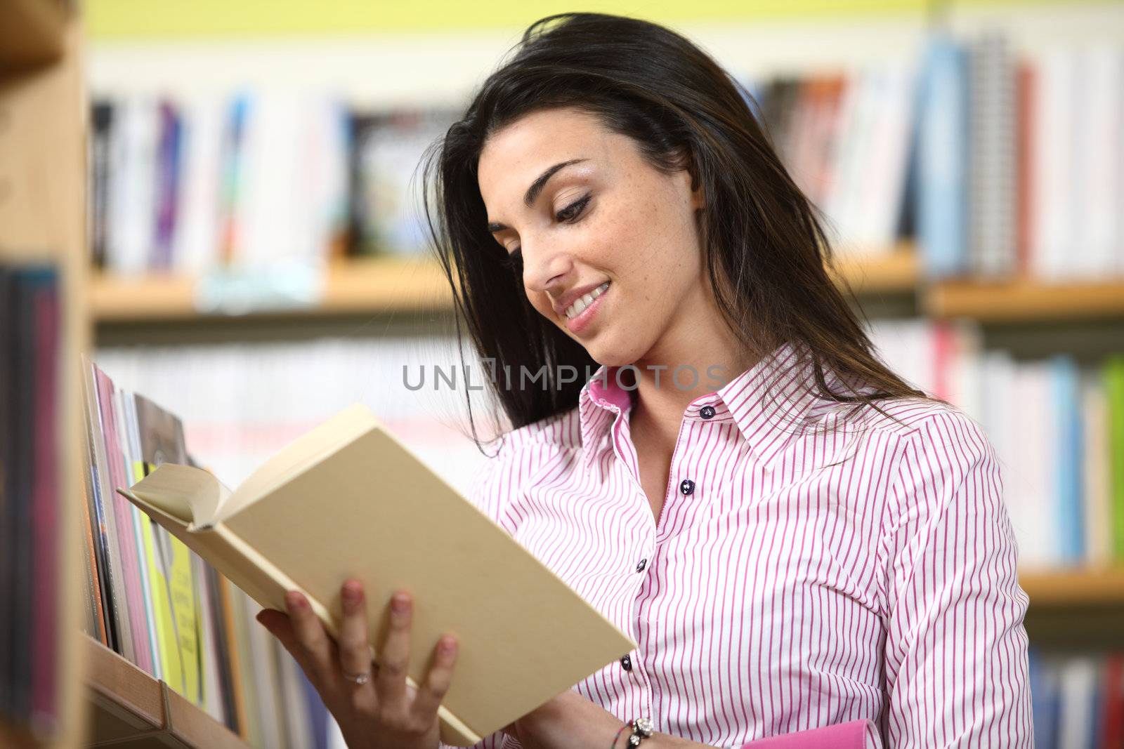 smiling female student reading a book in a bookstore 