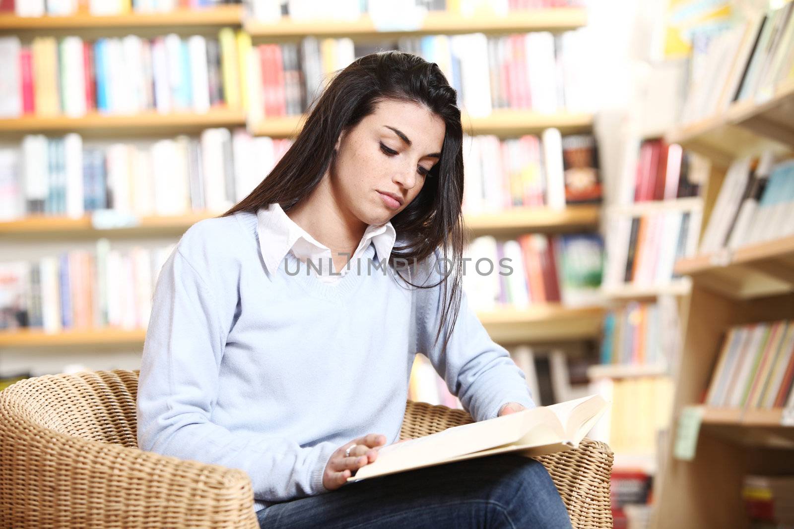 female student reading a book in library