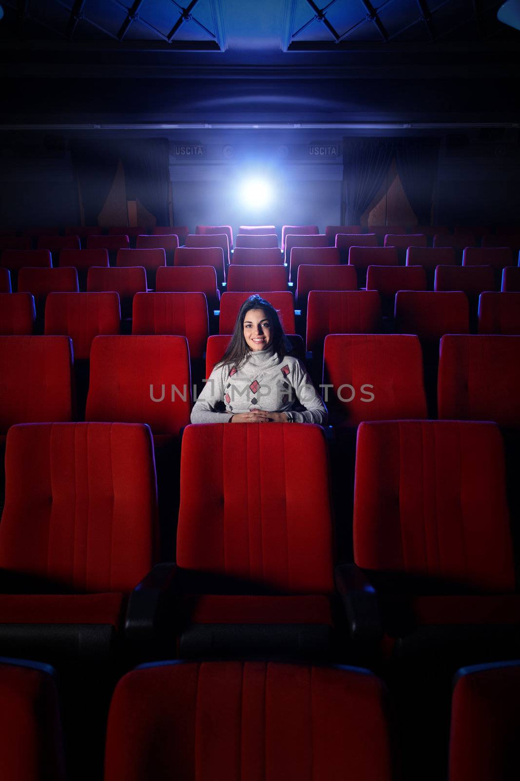 beautiful young woman alone sitting in a empty movie theater