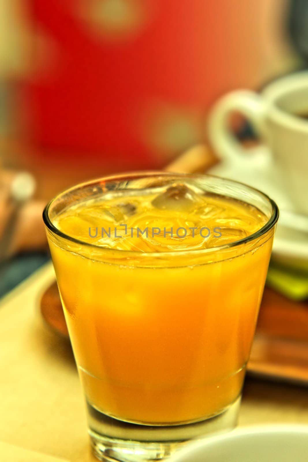 Glass of juice with ice cubes, next to a coffee mug