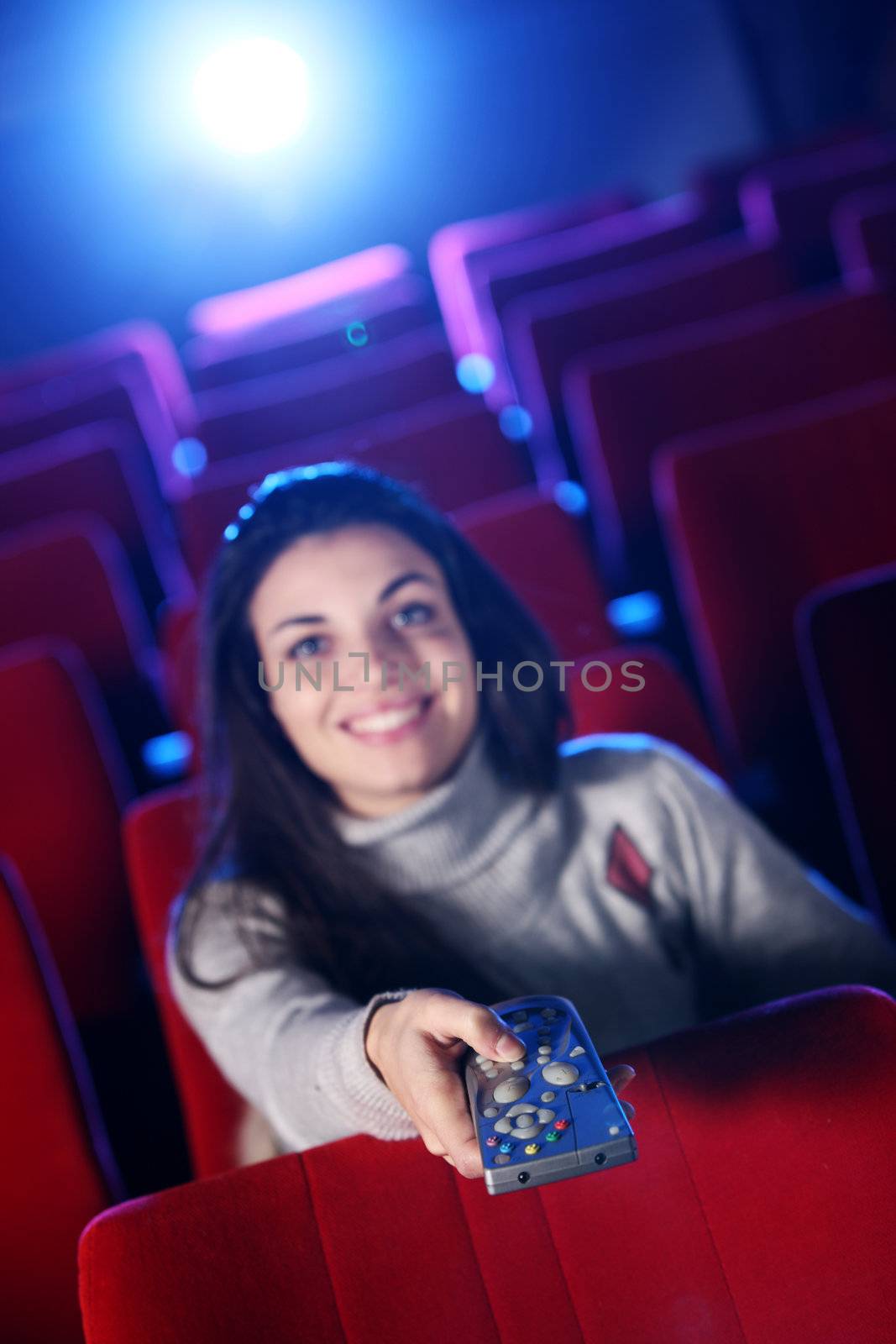 woman  holding a remote control TV, at a  movie theater. conceptual image