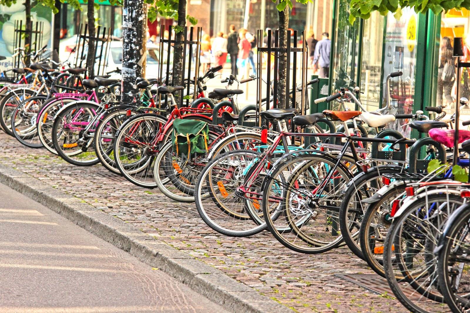 Bikes parked in the city, in a nice line into a rack by Arvebettum