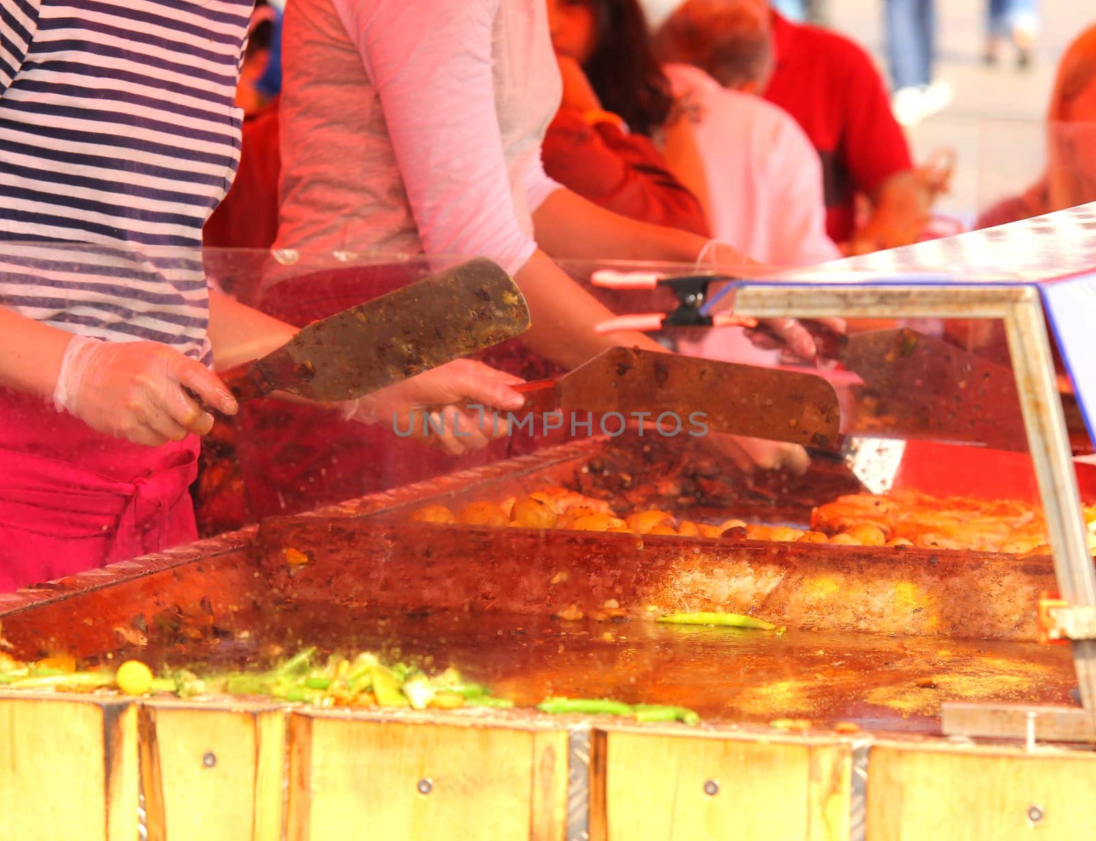 Chefs cooking at an outdoor restaurant, closeup by Arvebettum