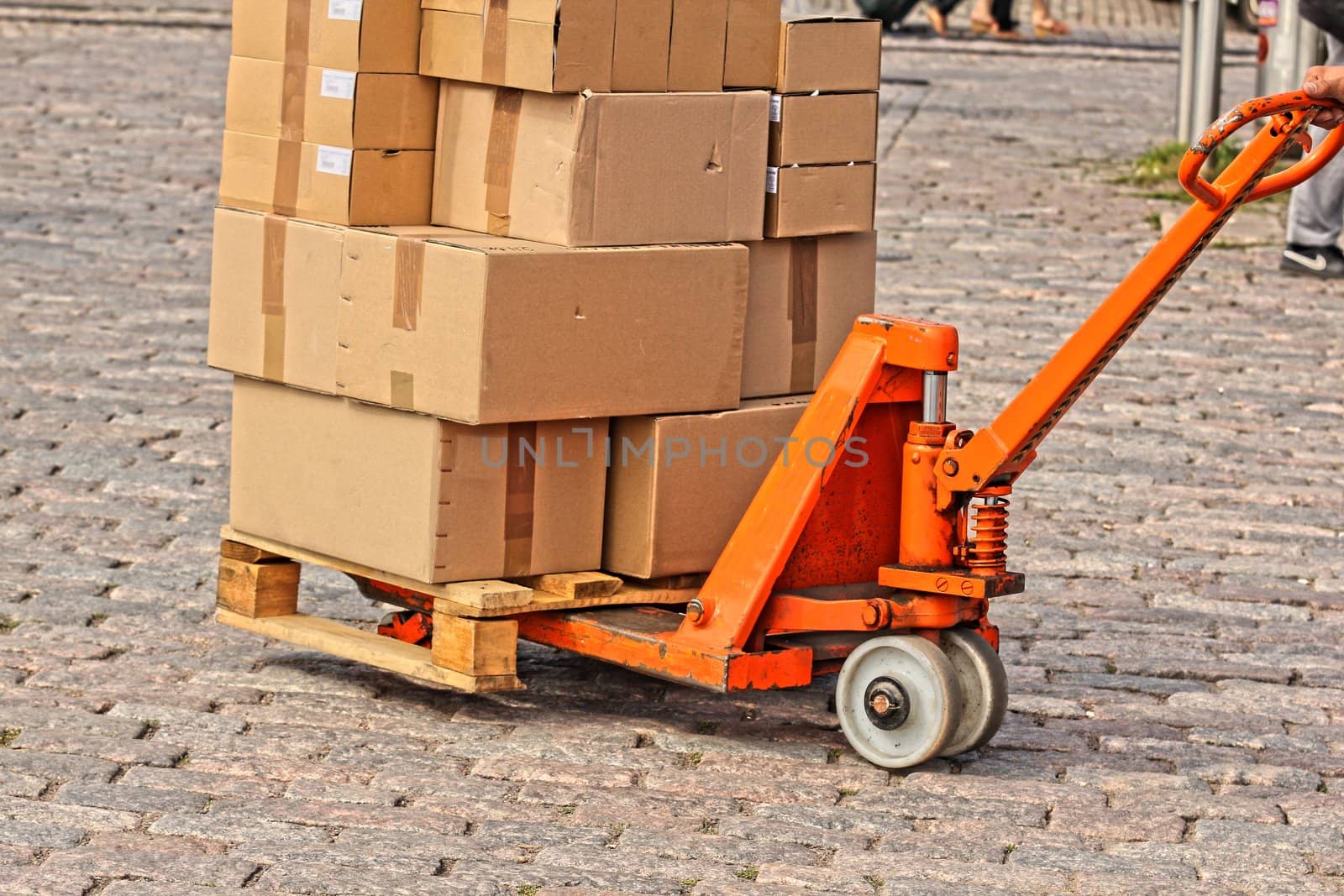 Courier shipping carboard boxes on a orange trolly, on stone floor