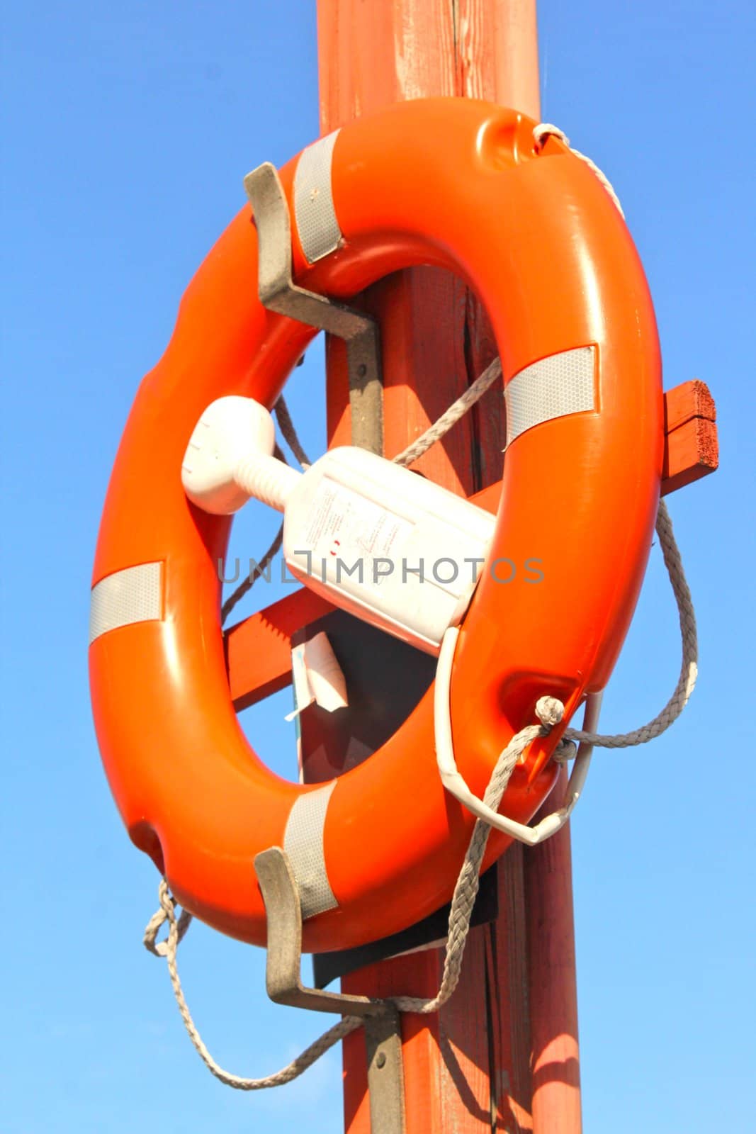 Life buoy attached to a pole towards blue sky by Arvebettum