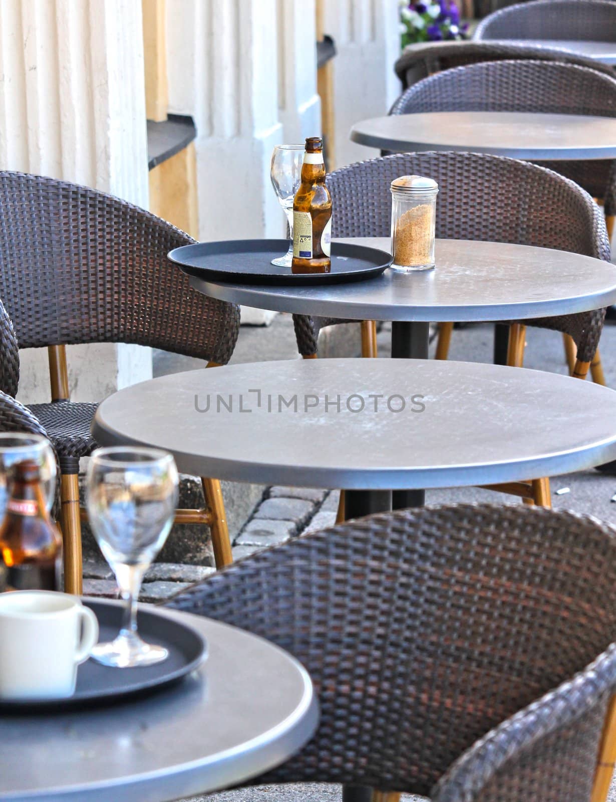 Restaurant outdoors, beer bottle on table, nobody around by Arvebettum