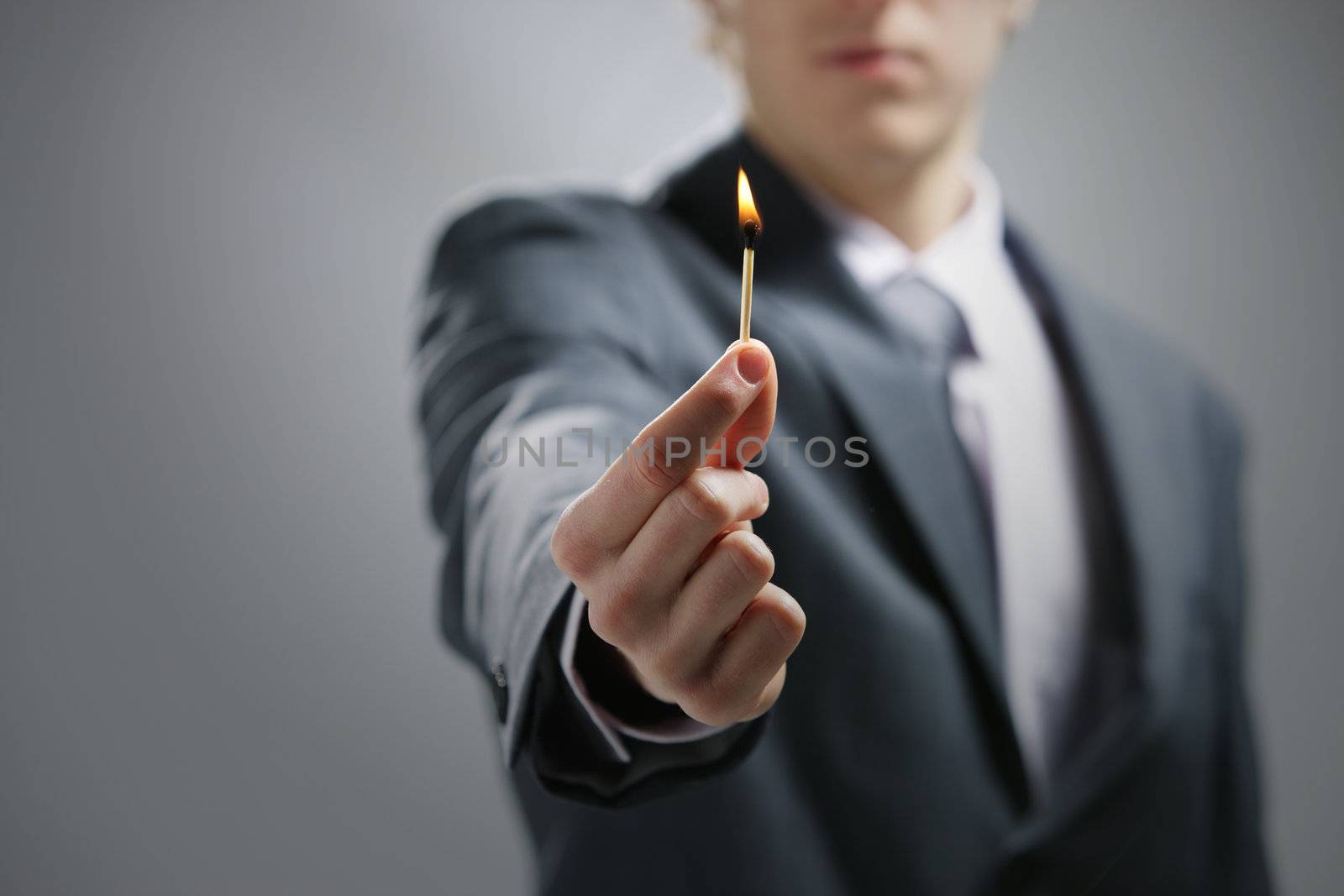 Business man hand holding a burning match by stokkete