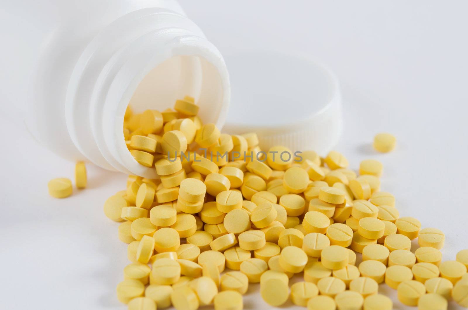 yellow medicine out of white bottle on white background
