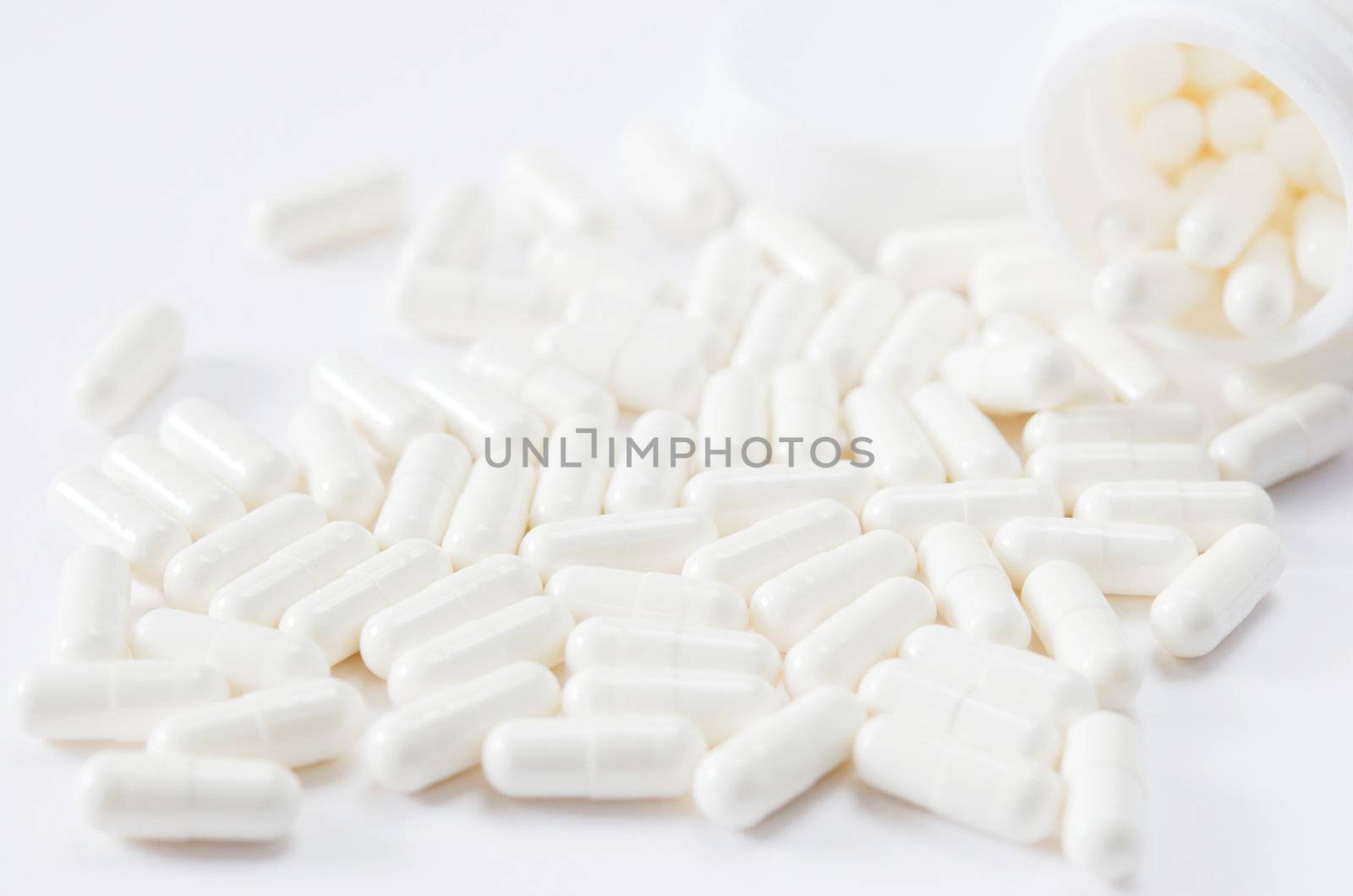 pills spilling out of pill bottle on white background