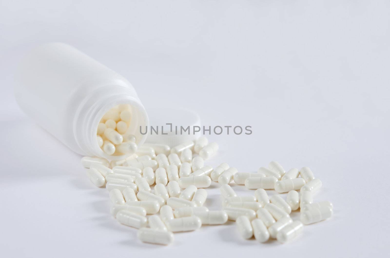 pills spilling out of  pill bottle on white background