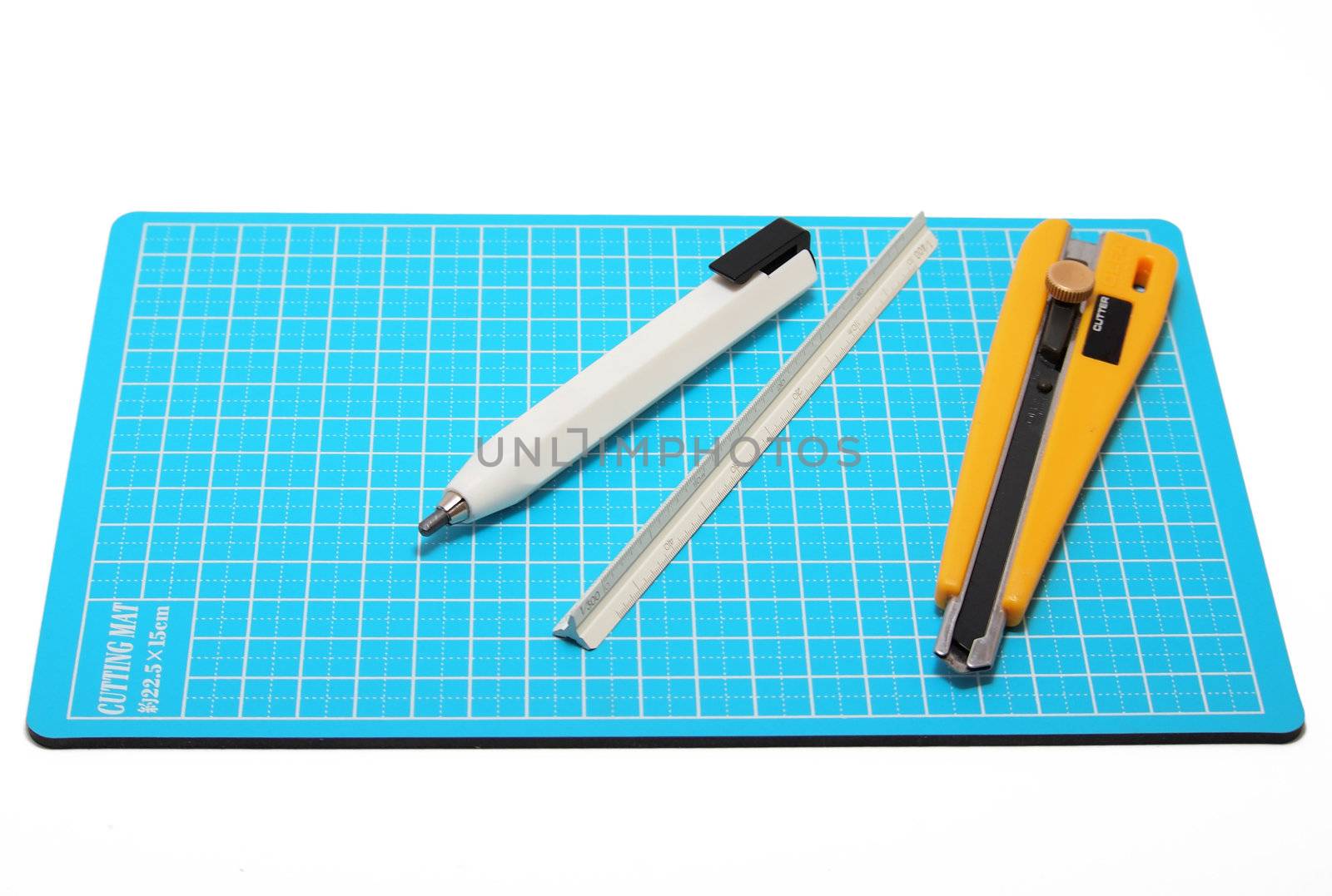 Cutter,pencil and Scale placed on blue cutting mat. by siraanamwong