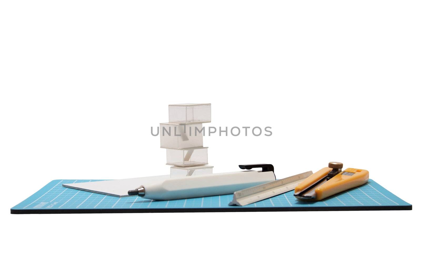 Cutter,pencil,scale and architectural model placed on blue cutting mat.       