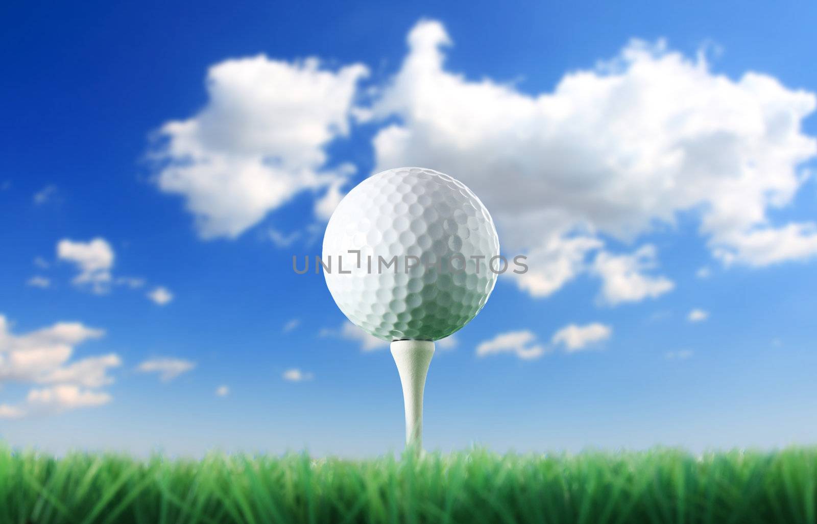 Golf ball in the grass against a  blue sky