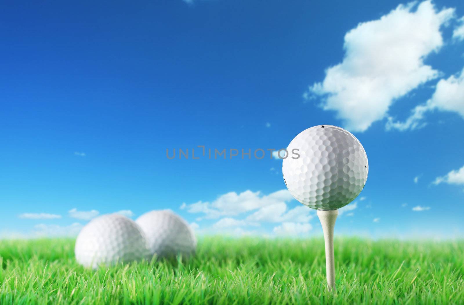 Golf ball in the grass against a  blue sky