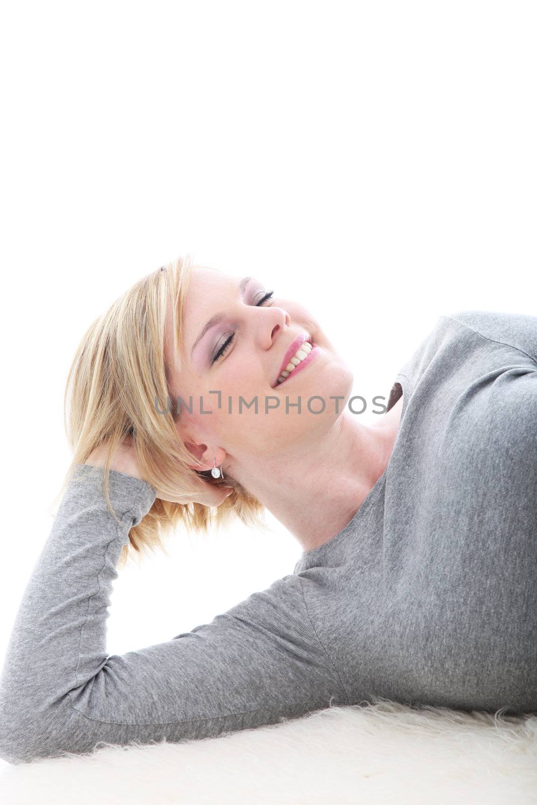 Attractive young blonde woman relaxing on the floor with her head tilted back and her eyes closed in bliss
