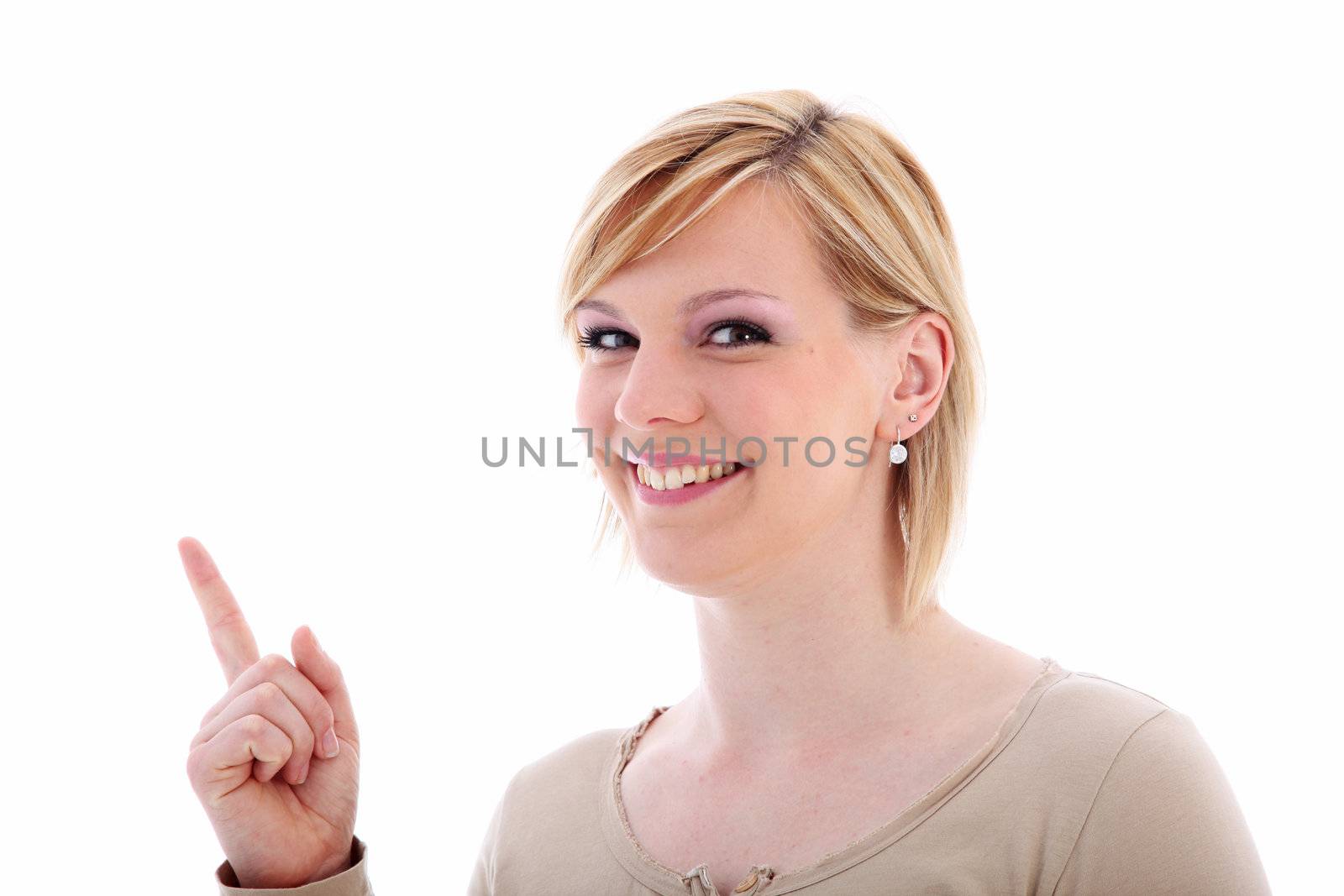 Friendly woman with a lovely smile pointing with her index finger to blank copyspace for your marketing or advertising