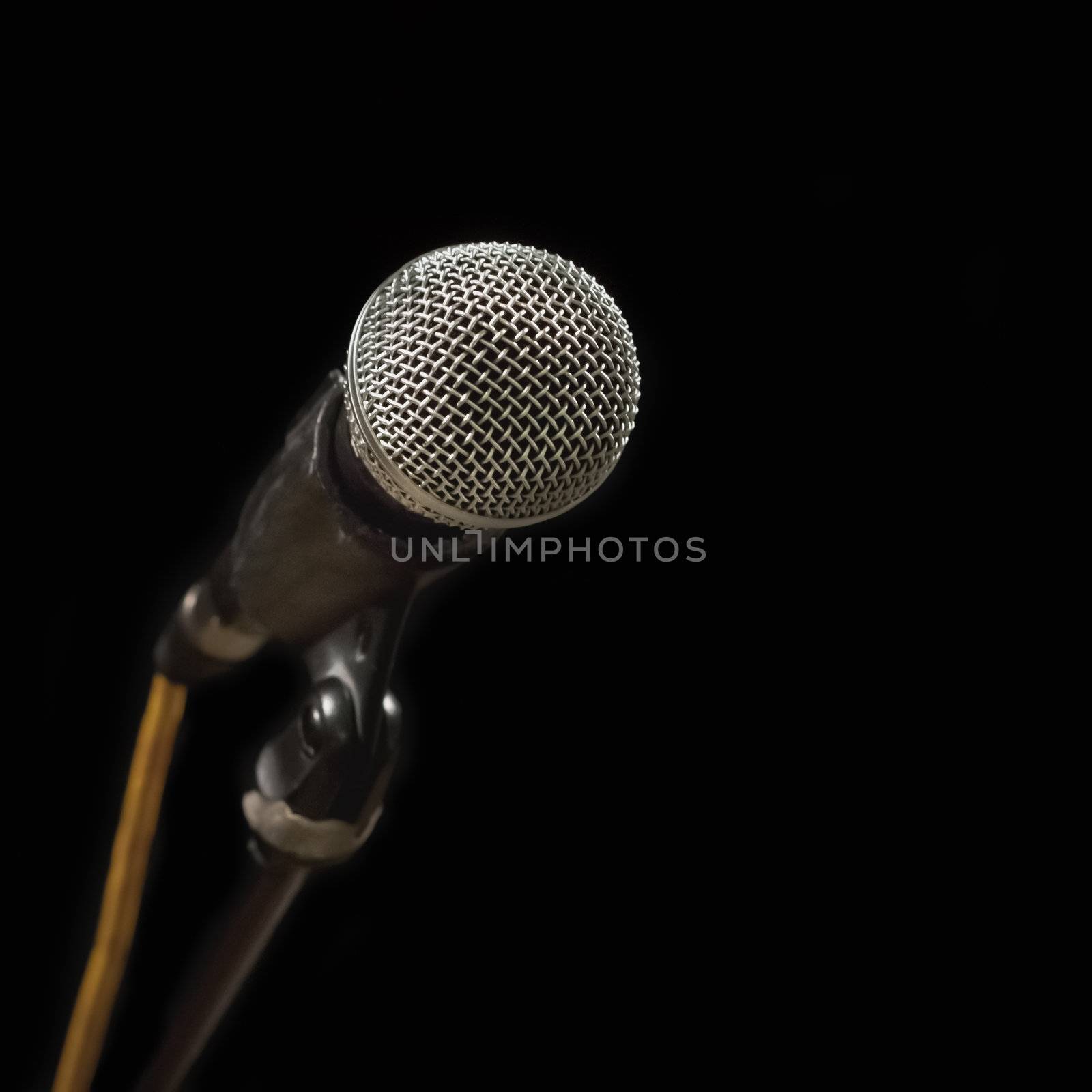 Classic black microphone on black stand. Isolated black background