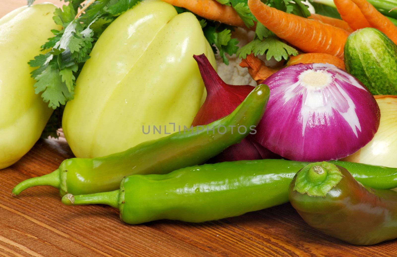 Vegetable Set of Green Bell Pepper, Chili peppers, Red Onion, Carrot and greens closeup on wooden background
