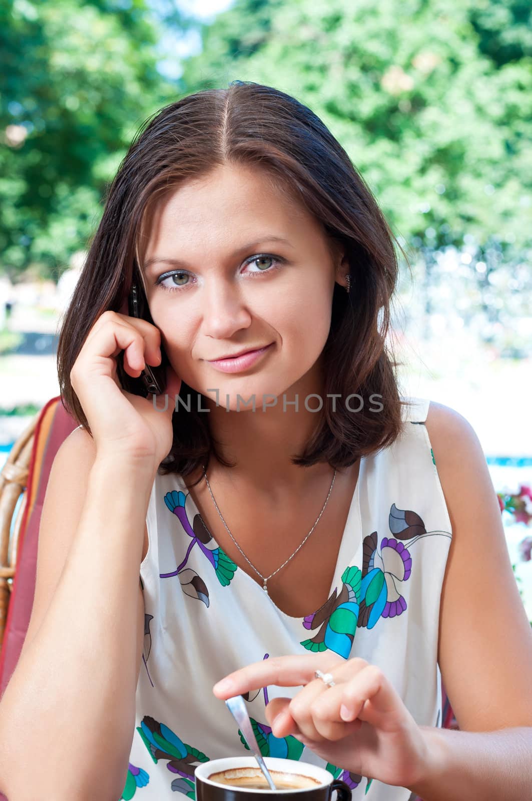 Girl in the cafe with a cup of coffee talking on cell phone.