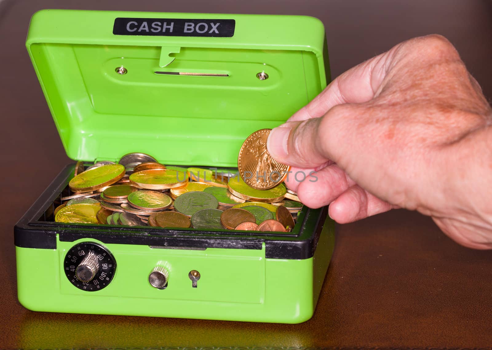 Green cash box with combination lock open to show piles of coins including gold and silver