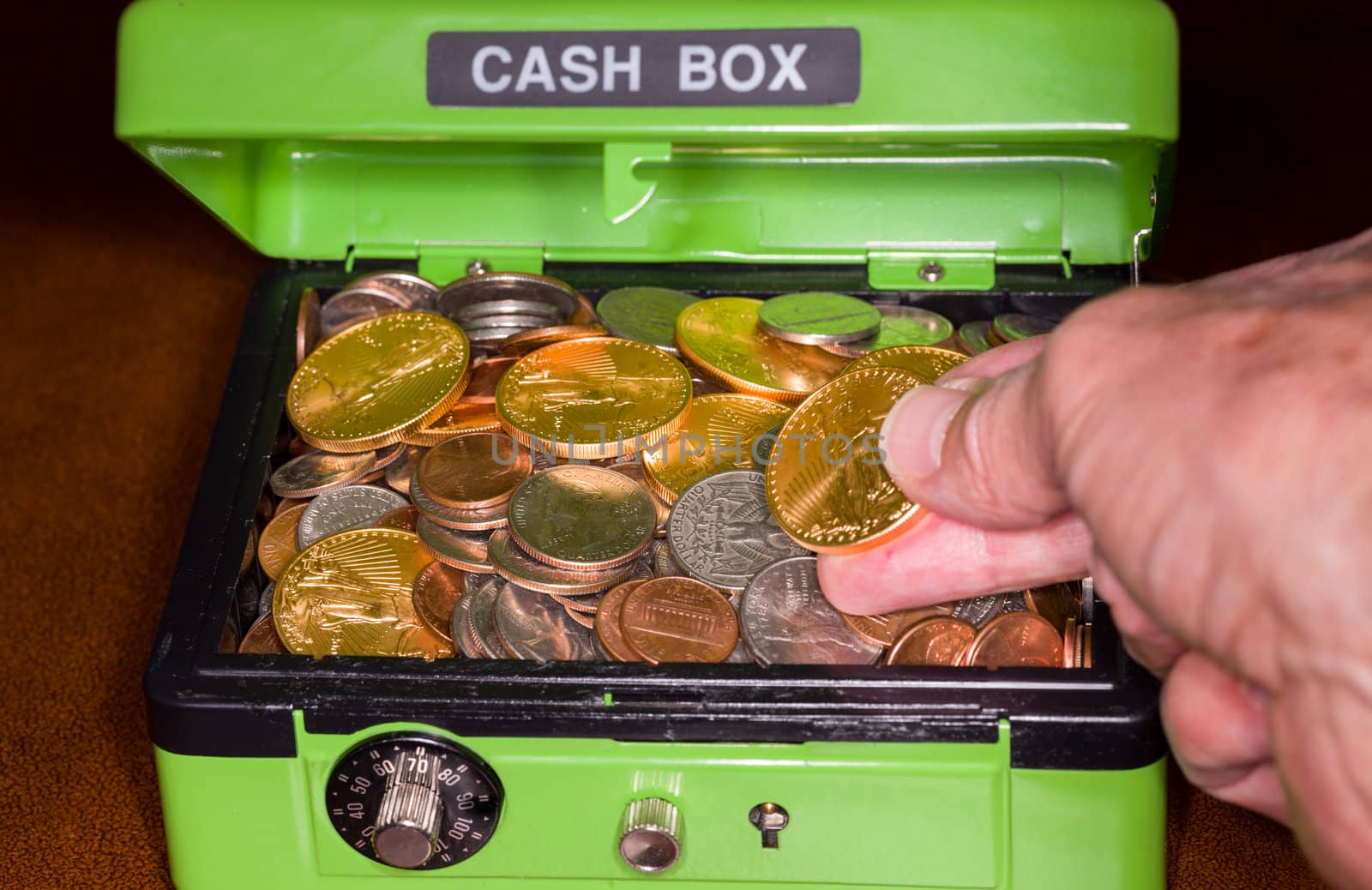 Green cash box with combination lock open to show piles of coins including gold and silver