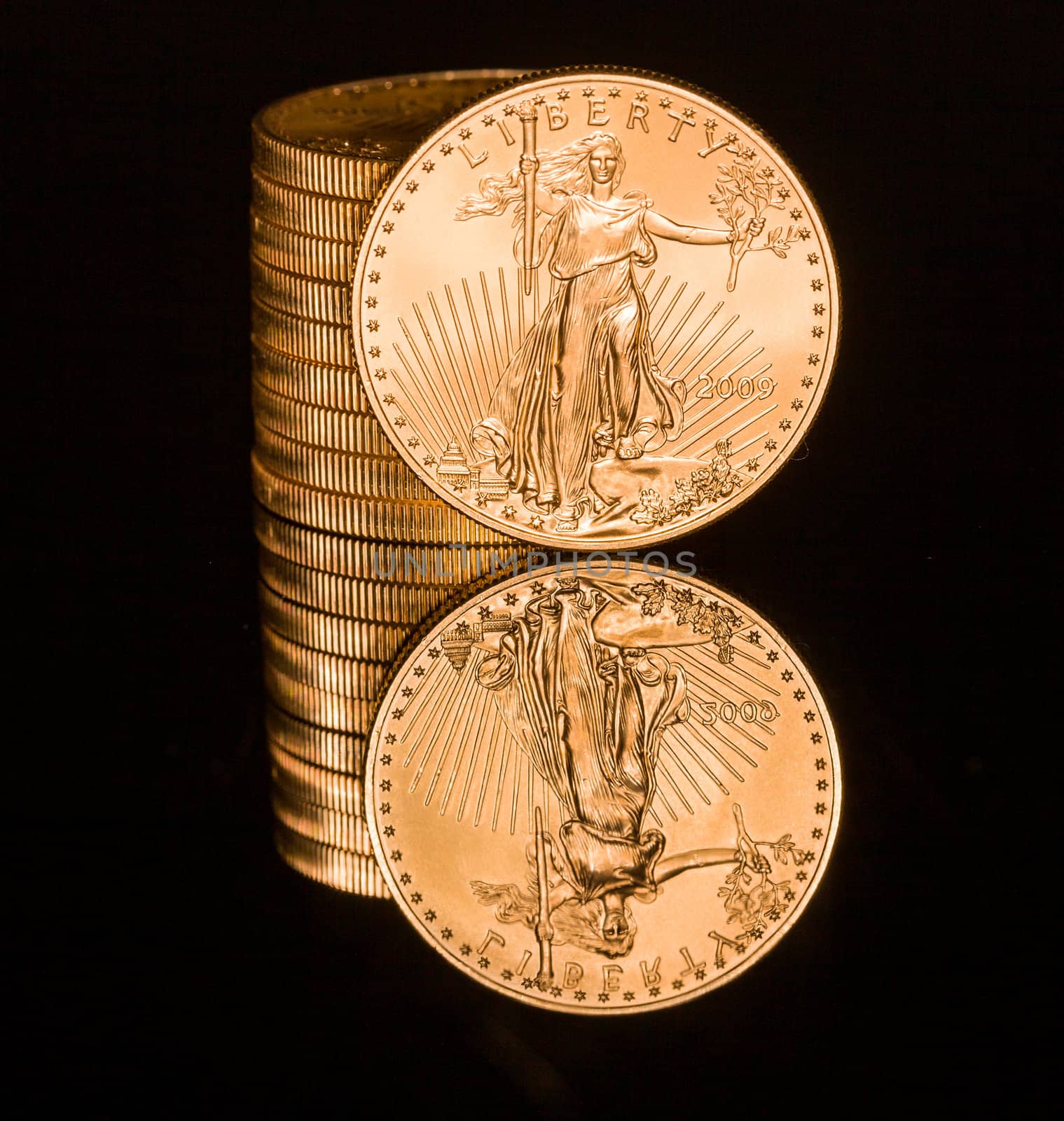 Reflection of single gold coin and stack on black polished surface