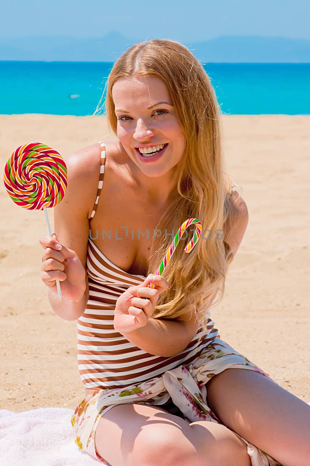 A young and beautiful woman with a lollipop resting on the beach